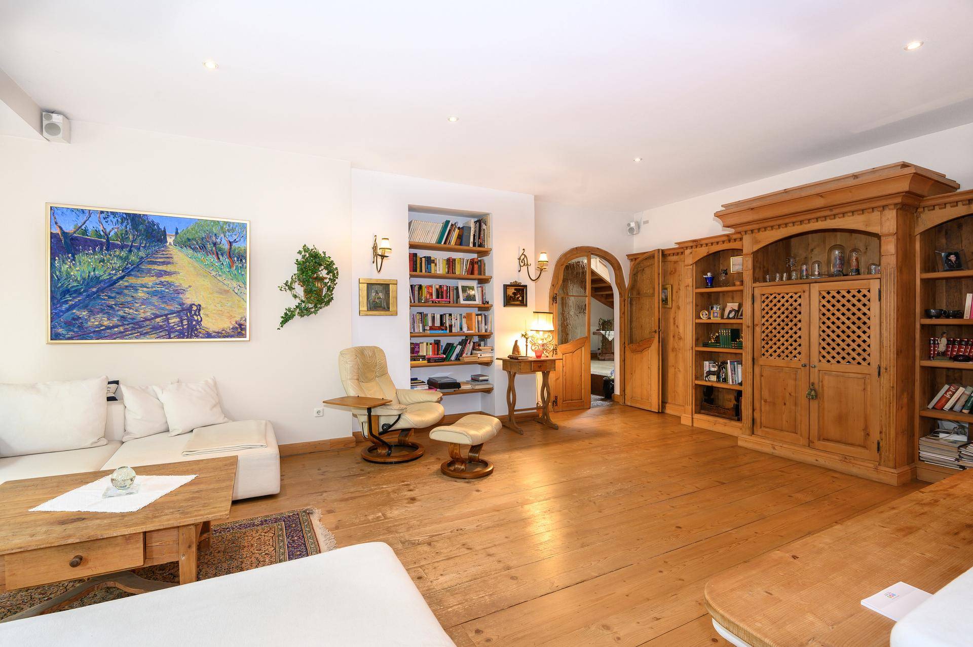 Gemütliches Wohnzimmer mit Holzdielenboden, Bücherregalen und traditionellen Holzmöbeln.