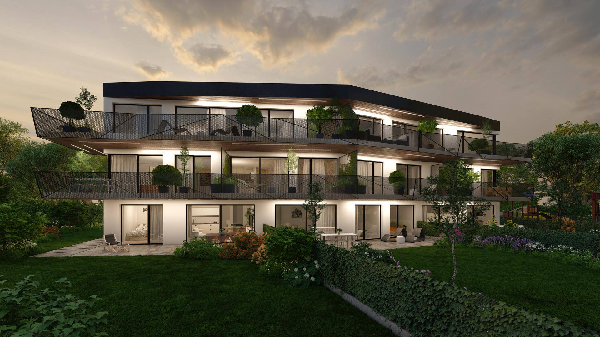 Beleuchtete moderne Wohnanlage am Abend mit Balkonen, Terrassen und einem gepflegten Gartenbereich.