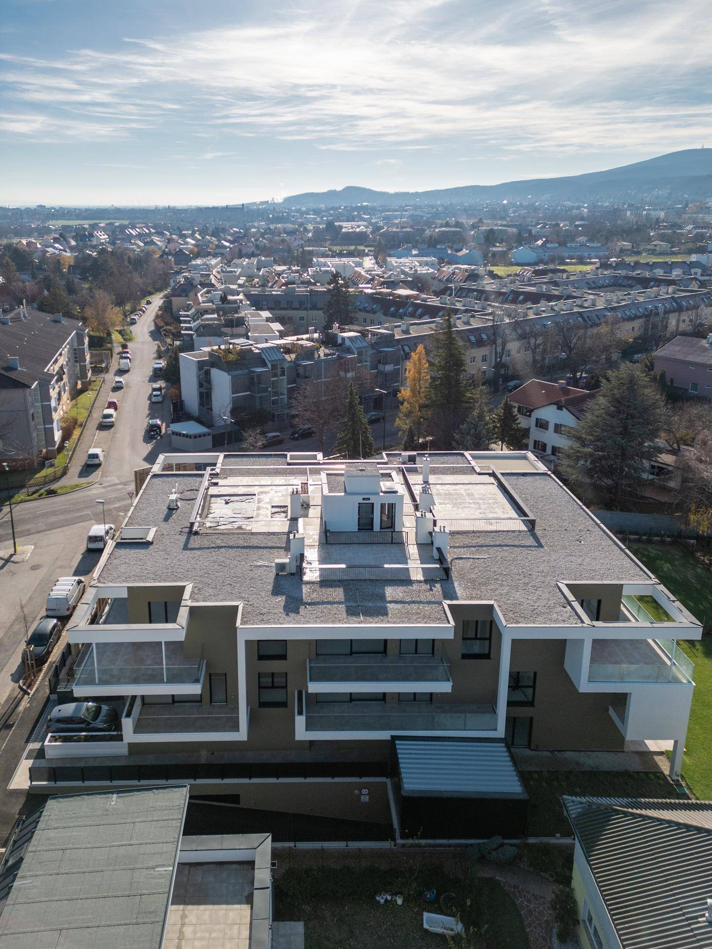 Luftaufnahme eines modernen Wohnkomplexes mit Flachdach und umliegender städtischer Bebauung.