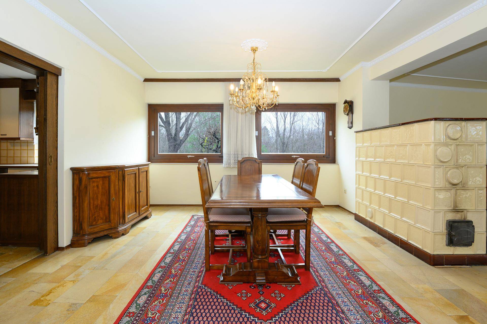 Klassischer Essbereich mit Holztisch, Kachelofen und Fliesenboden, ideal für Familienessen.
