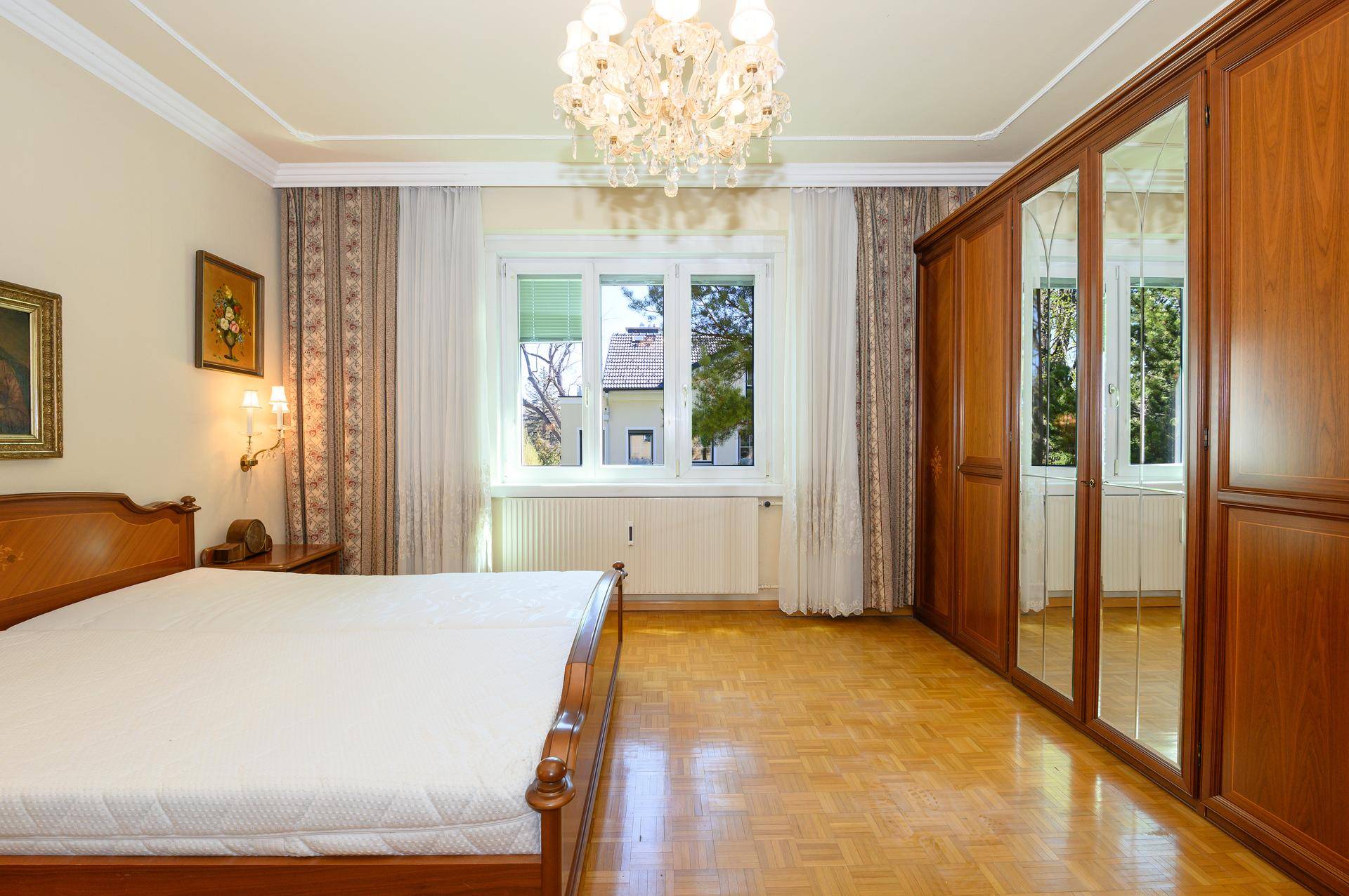 Helles Schlafzimmer mit Doppelbett, großem Spiegelschrank und Parkettboden.