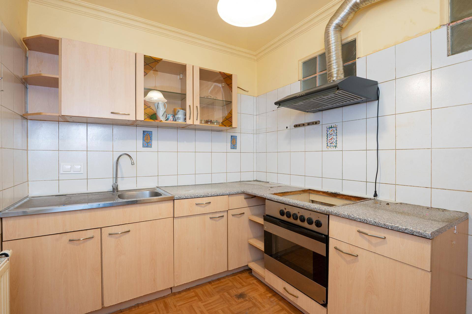 Helle Küche mit beigen Holzschränken, Fliesenrückwand und Dunstabzugshaube.