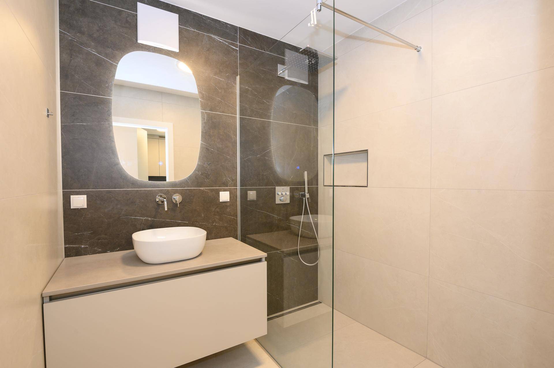 Modernes Badezimmer mit großformatigen Fliesen, Einzelwaschbecken und einer begehbaren Dusche.