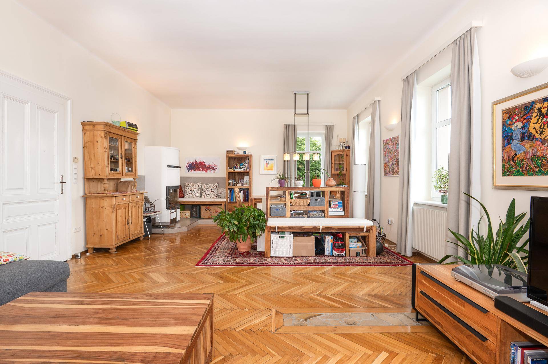 Geräumiger Wohnbereich mit Holzboden, Kachelofen und traditionellen Holzmöbeln.