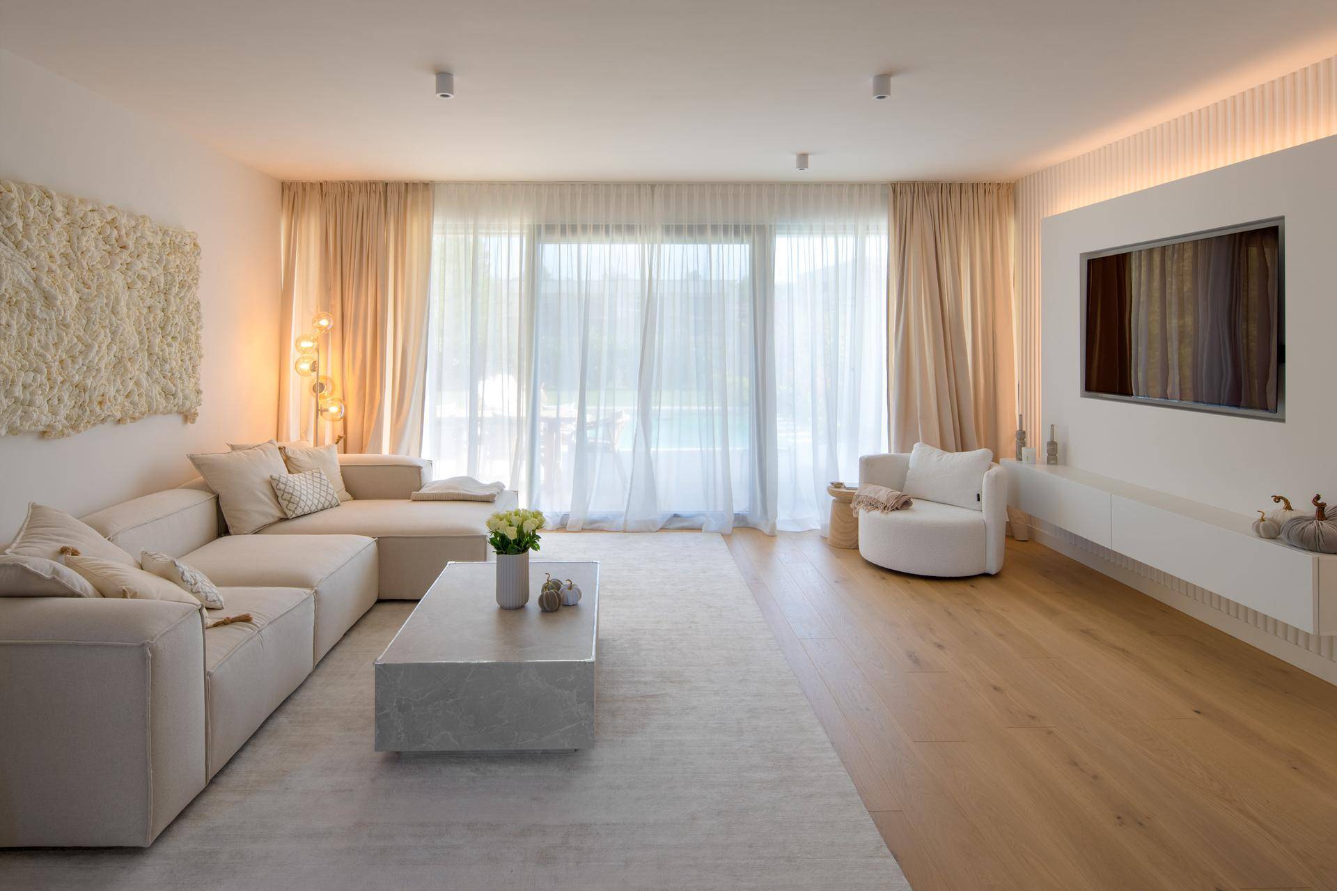 Helles, modernes Wohnzimmer mit großem Sofa, Holzboden und bodentiefen Fenstern für viel Tageslicht.