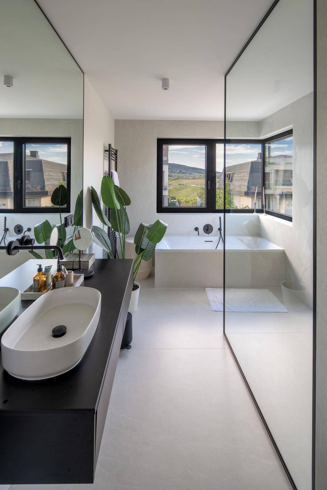 Modernes Badezimmer mit eingebauter Badewanne, Doppelwaschbecken und großem Fenster mit Weitblick.