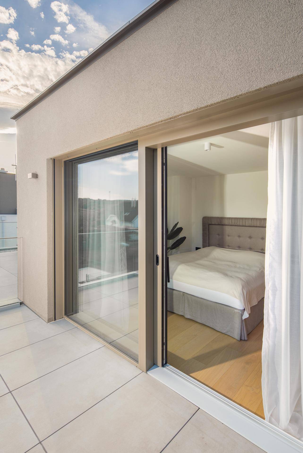Helles Schlafzimmer mit Zugang zu einer Terrasse durch große Glasschiebetüren.