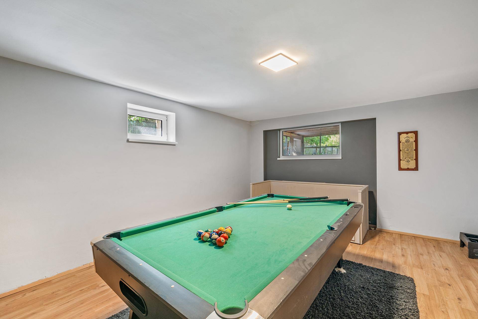 Spielzimmer im Untergeschoss mit Billardtisch und kleinen Fenstern.