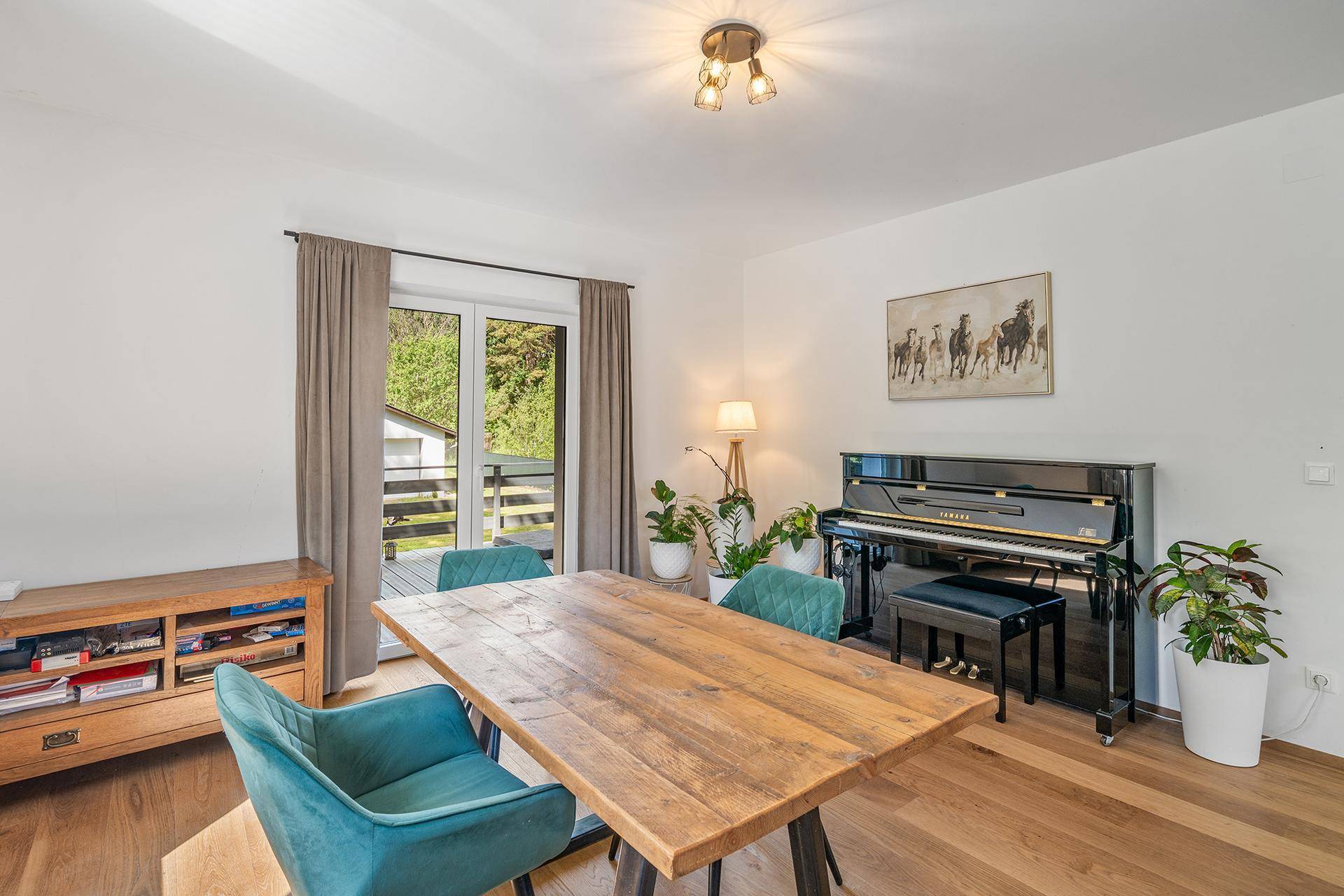 Gemütlicher Essbereich mit Holztisch, Klavier und Zugang zu einem Balkon.
