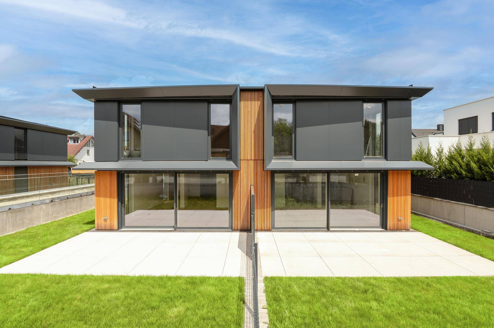 Ansicht der modernen Doppelhaushälften von hinten mit großzügigen Terrassen und Gärten.