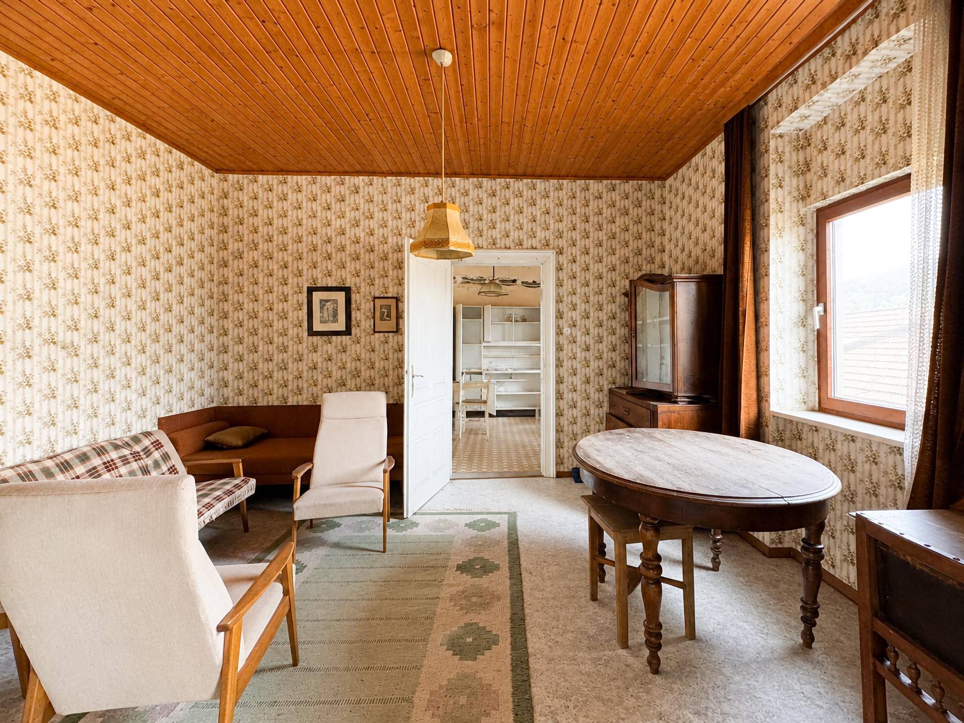 Wohnzimmer im Vintage-Stil mit gemusterter Tapete, Holzdecke und traditionellen Möbeln.