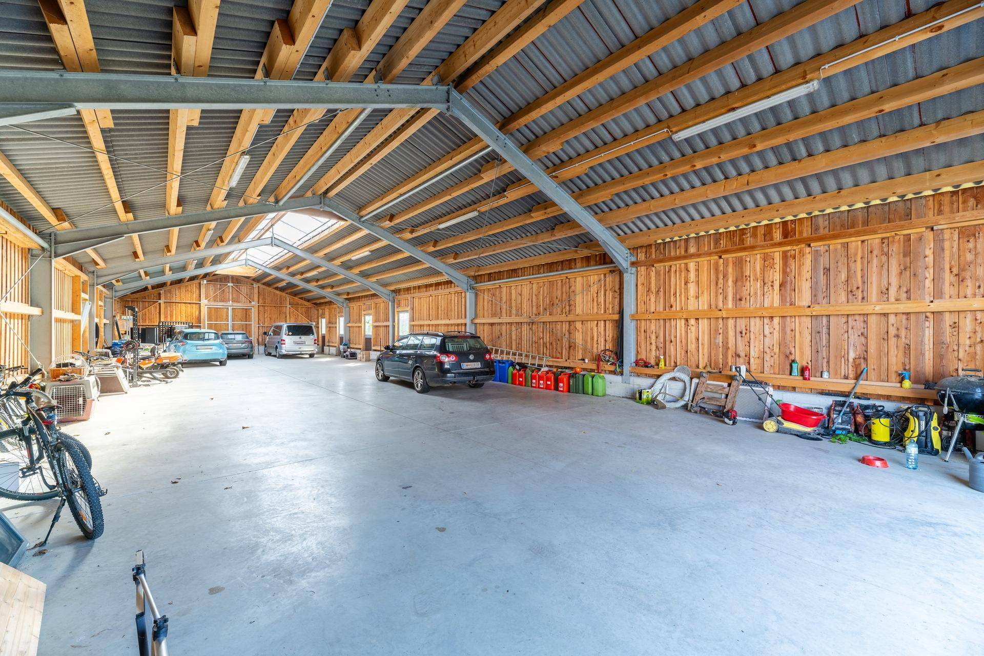Geräumige Garage oder Scheune mit Betonboden, Holzwänden und Platz für mehrere Fahrzeuge.
