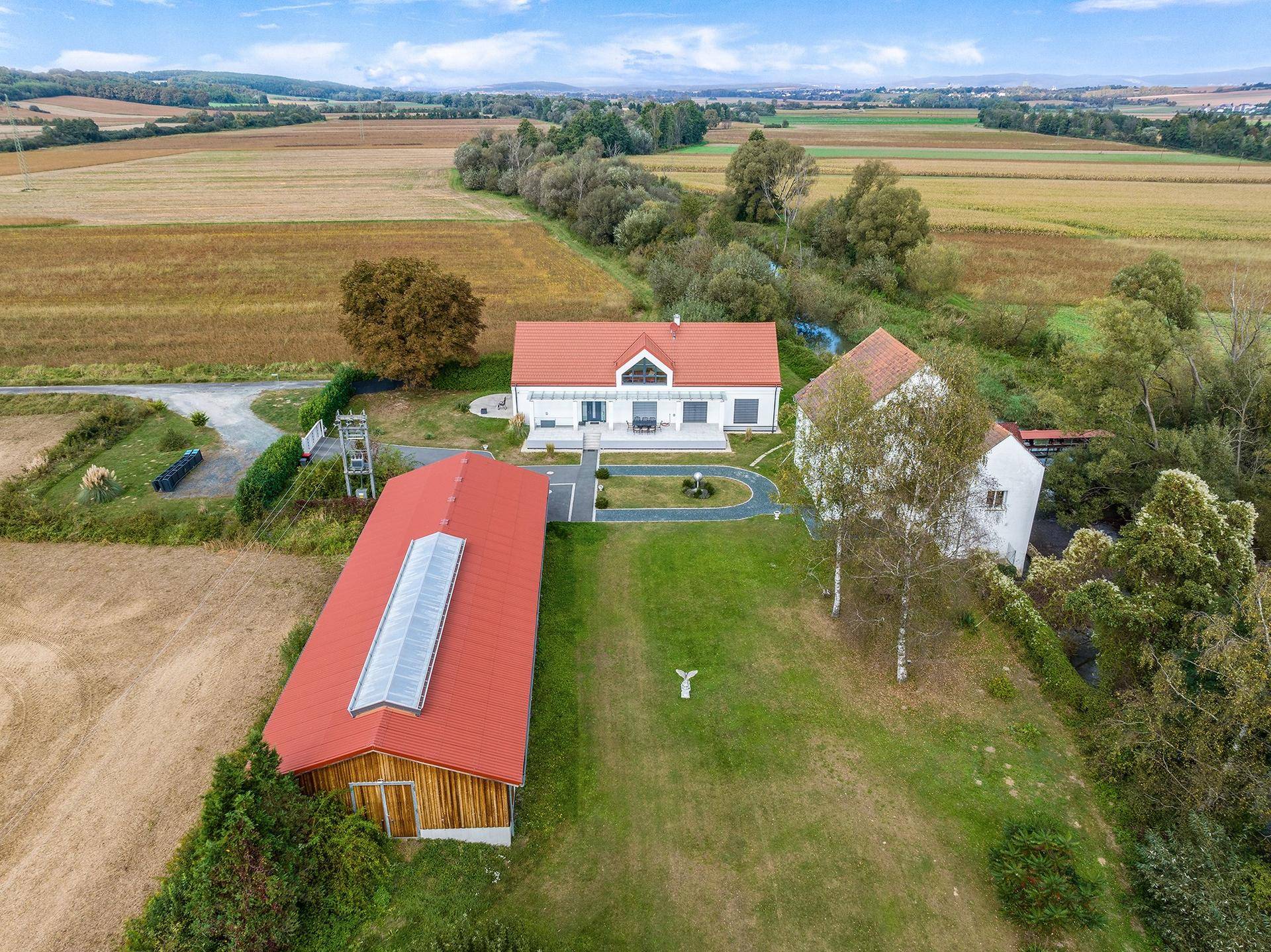 Panoramablick auf das Anwesen mit drei Gebäuden, darunter eine moderne Villa und ein großes Wirtschaftsgebäude.