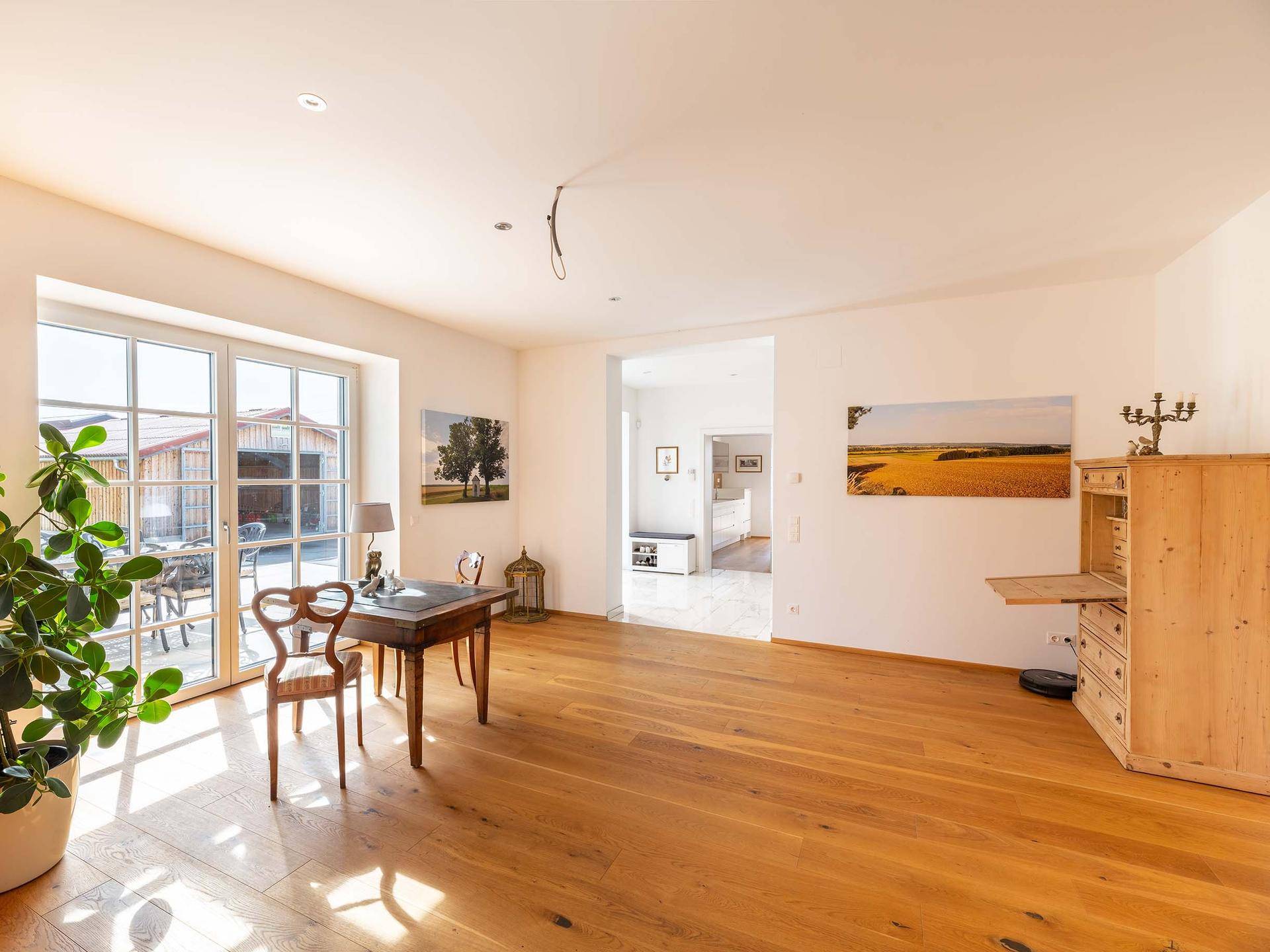 Helles Arbeitszimmer mit Holzboden, großen Glastüren und direktem Zugang zu einem Außenbereich.
