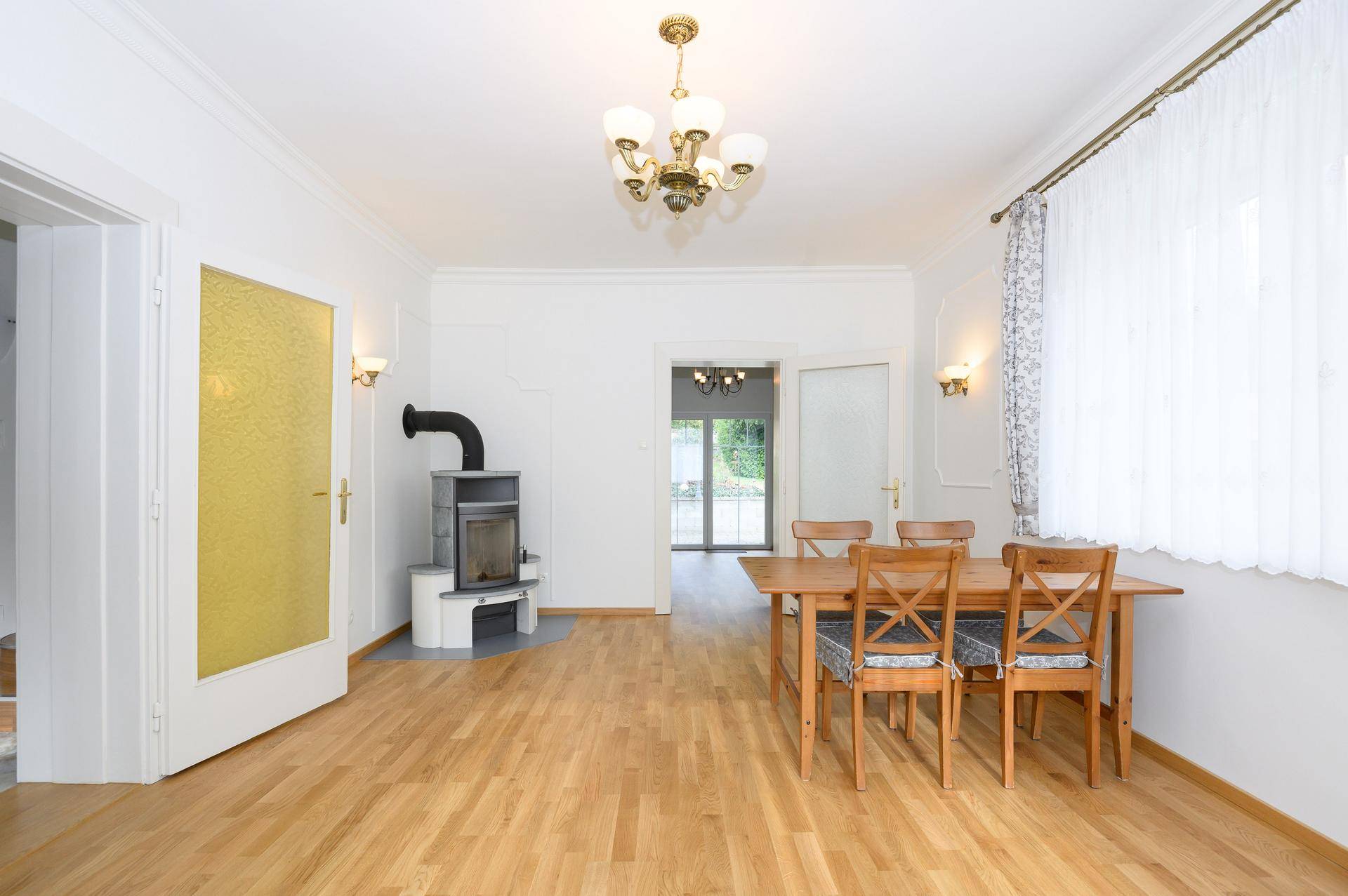 Heller Essbereich mit Holzboden, Kaminofen und einem Holztisch mit Stühlen.