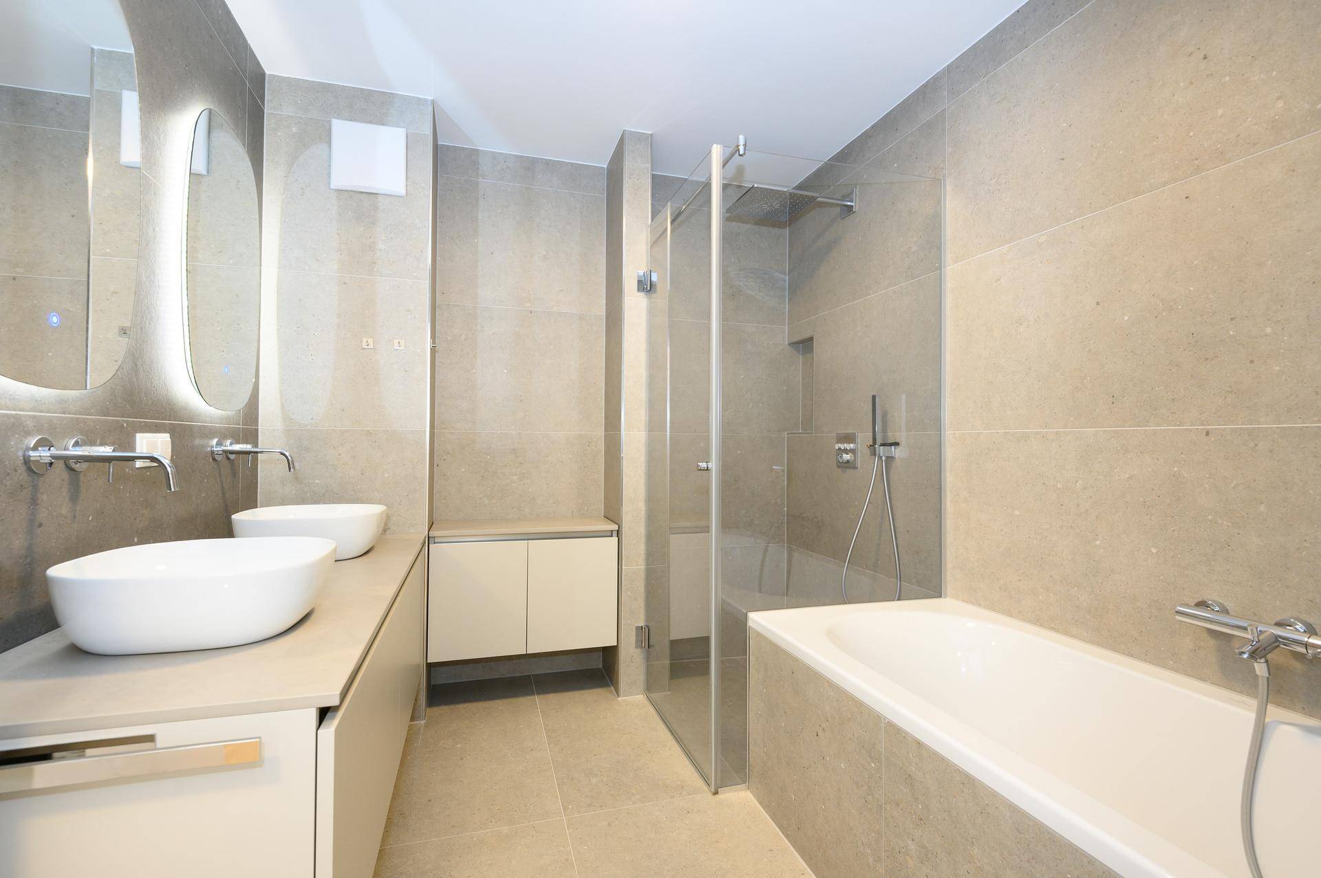 Modernes Badezimmer mit Doppelwaschbecken, Badewanne und separater Glasdusche.
