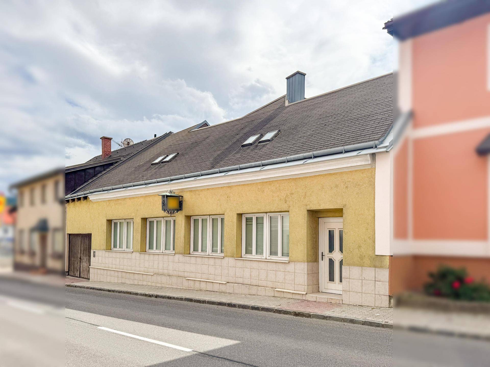 Traditionelles Gebäude mit gelber Fassade, weißen Fenstern und barrierefreiem Zugang.