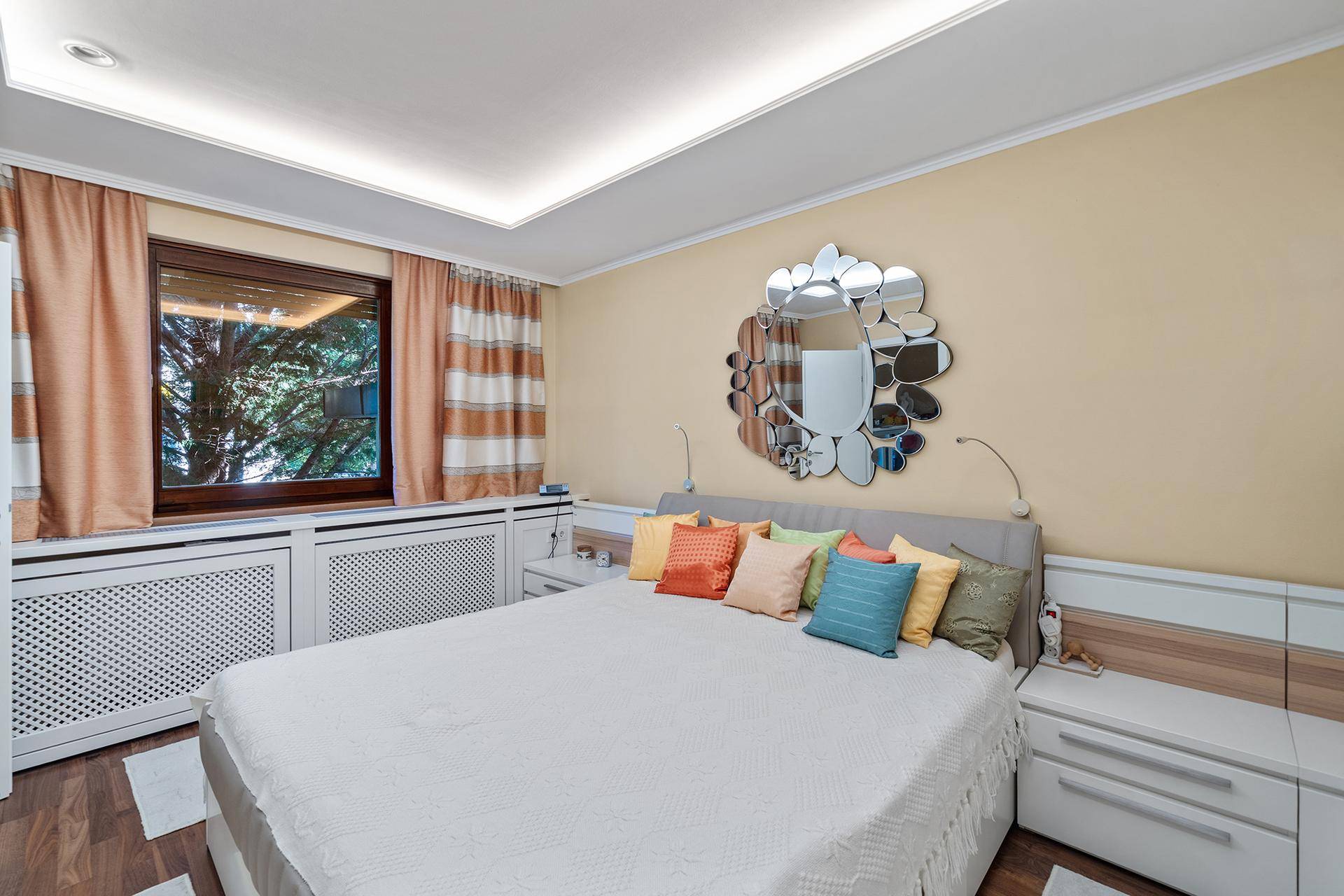Gemütliches Schlafzimmer mit großem Bett, Heizungsverkleidung und Blick ins Grüne.