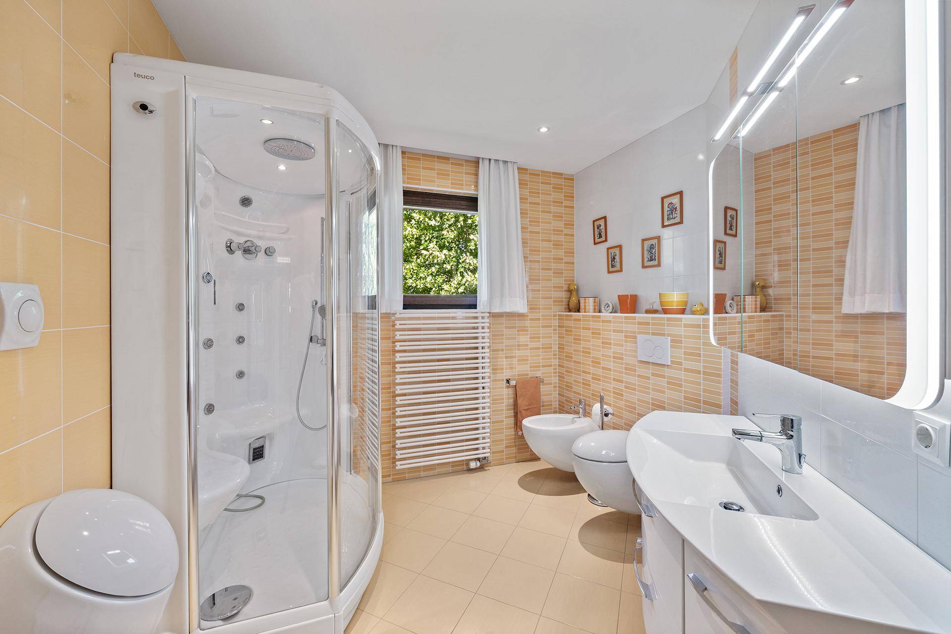 Helles Badezimmer mit Duschkabine, Bidet und beheiztem Handtuchhalter.