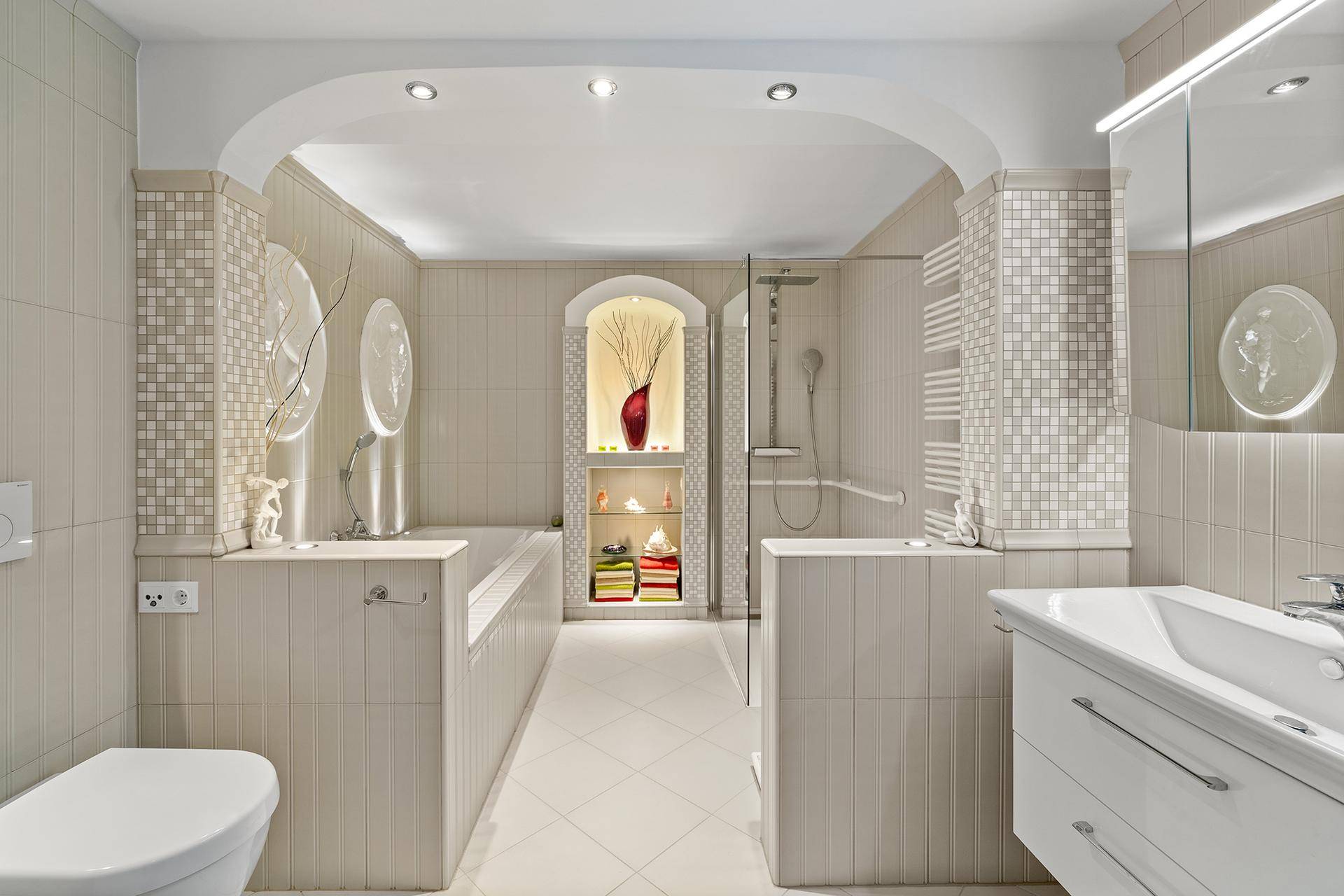 Helles Badezimmer mit Badewanne, Duschkabine und beigefarbenen Fliesen.