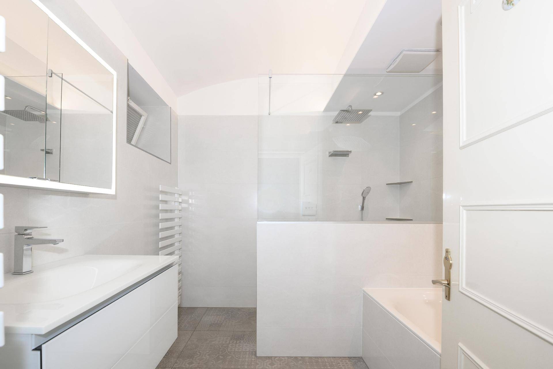 Modernes Badezimmer mit begehbarer Dusche, Badewanne und weißer Einrichtung.
