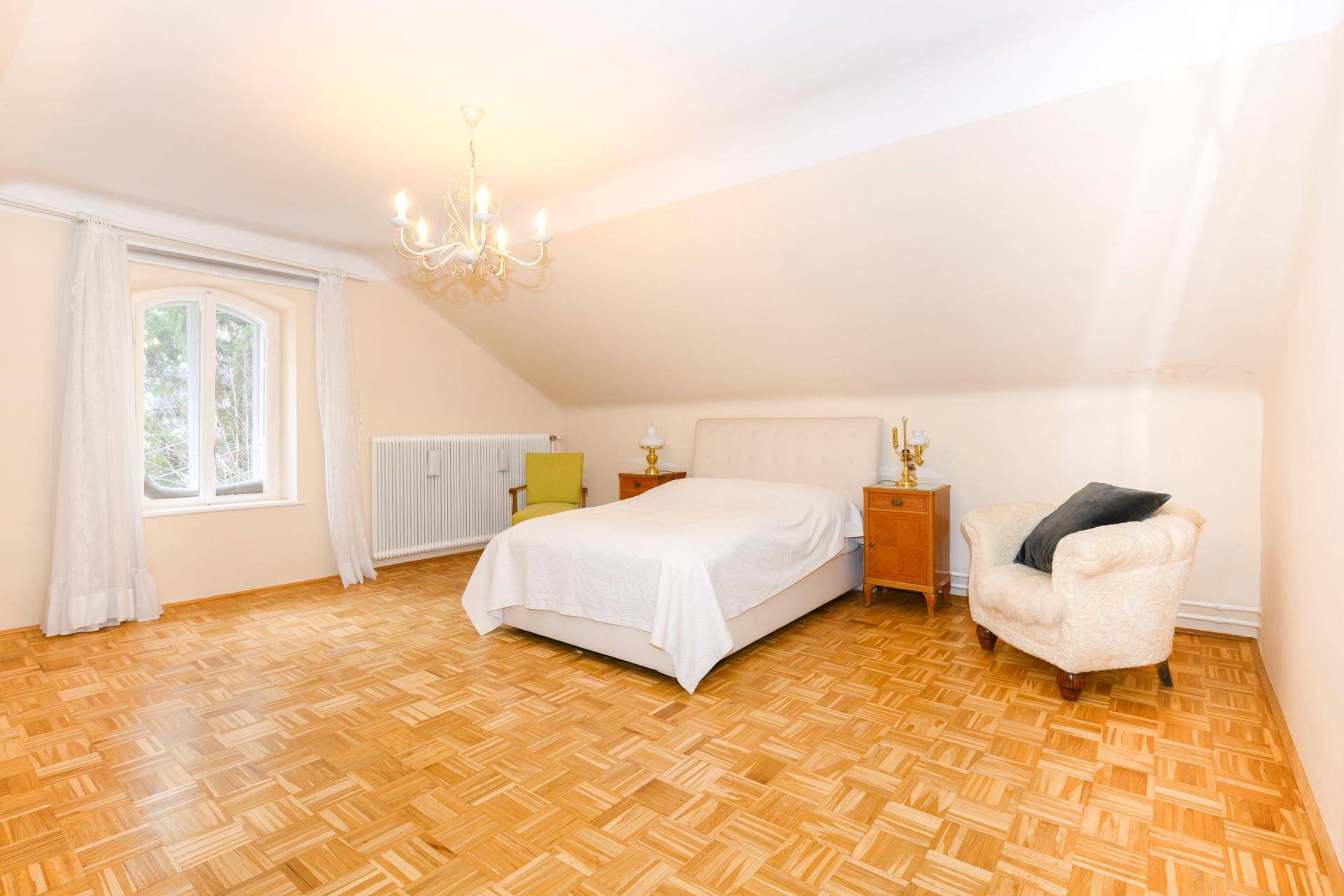 Geräumiges Schlafzimmer im Dachgeschoss mit Parkettboden und einem großen Fenster.