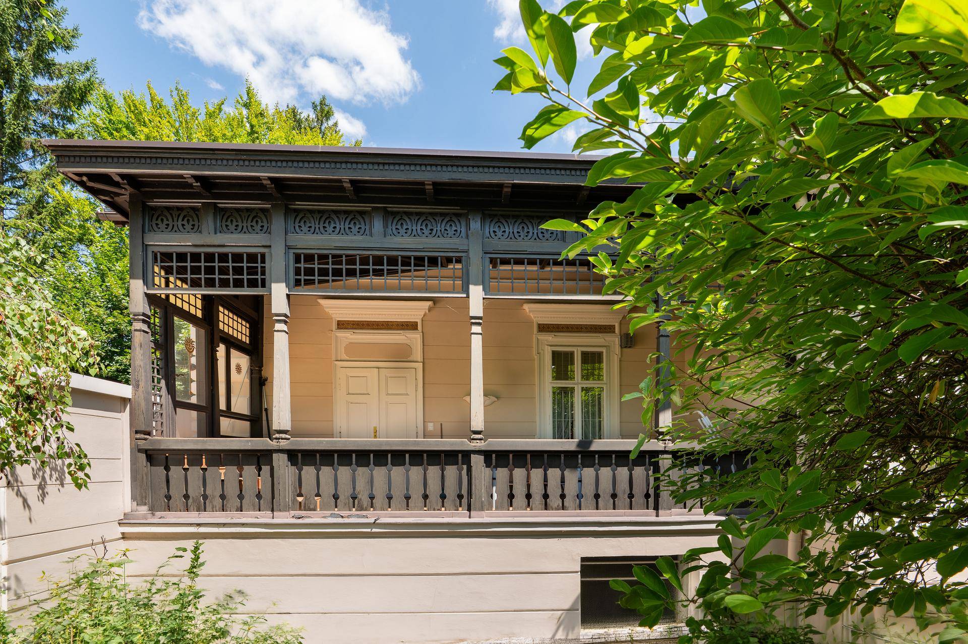 Historischer Balkon mit aufwendig geschnitztem Holzgeländer und Blick ins Grüne.