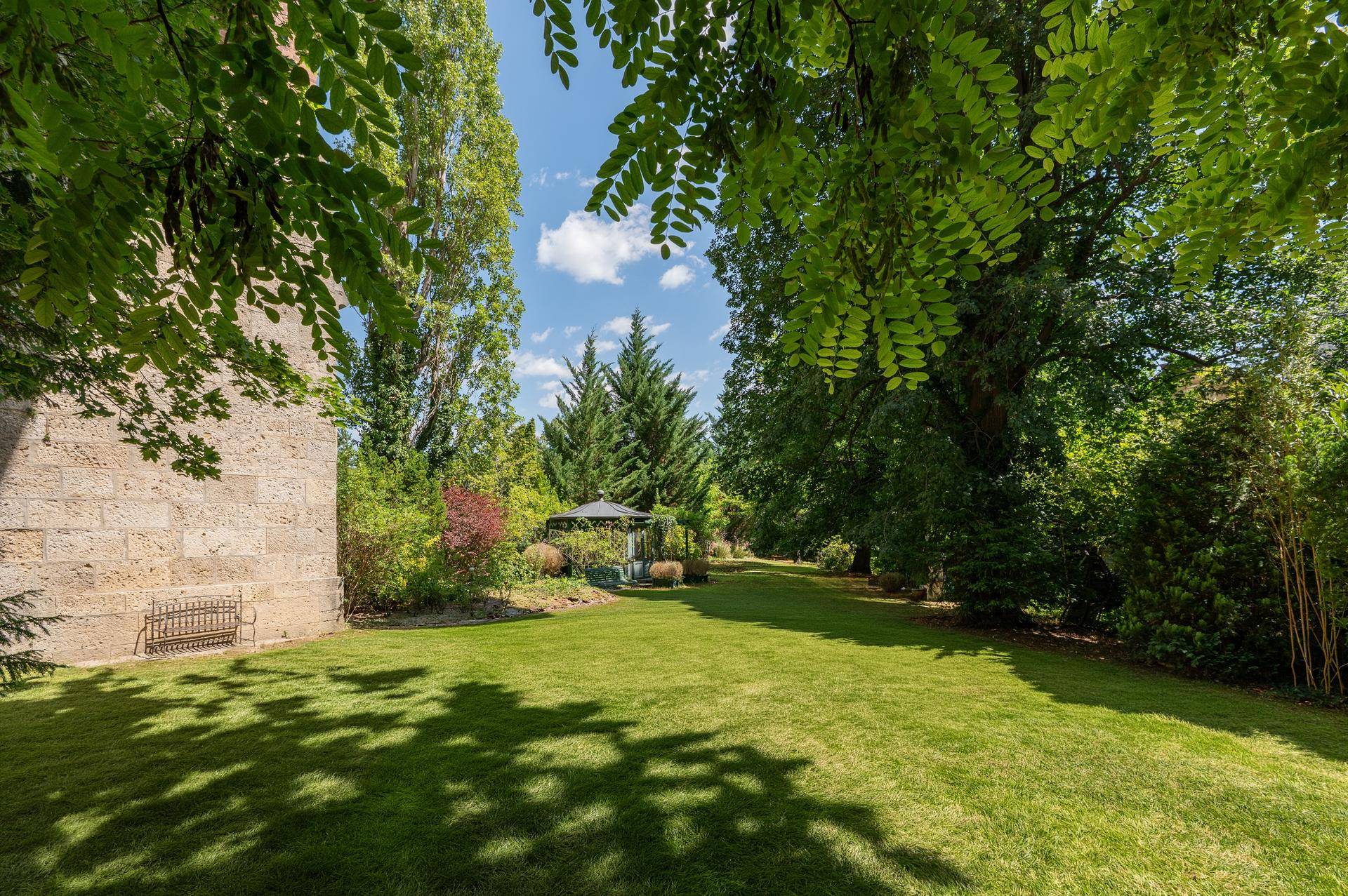 Weitläufiger Garten mit Rasenflächen, hohen Bäumen und viel Grün, ideal zur Erholung.