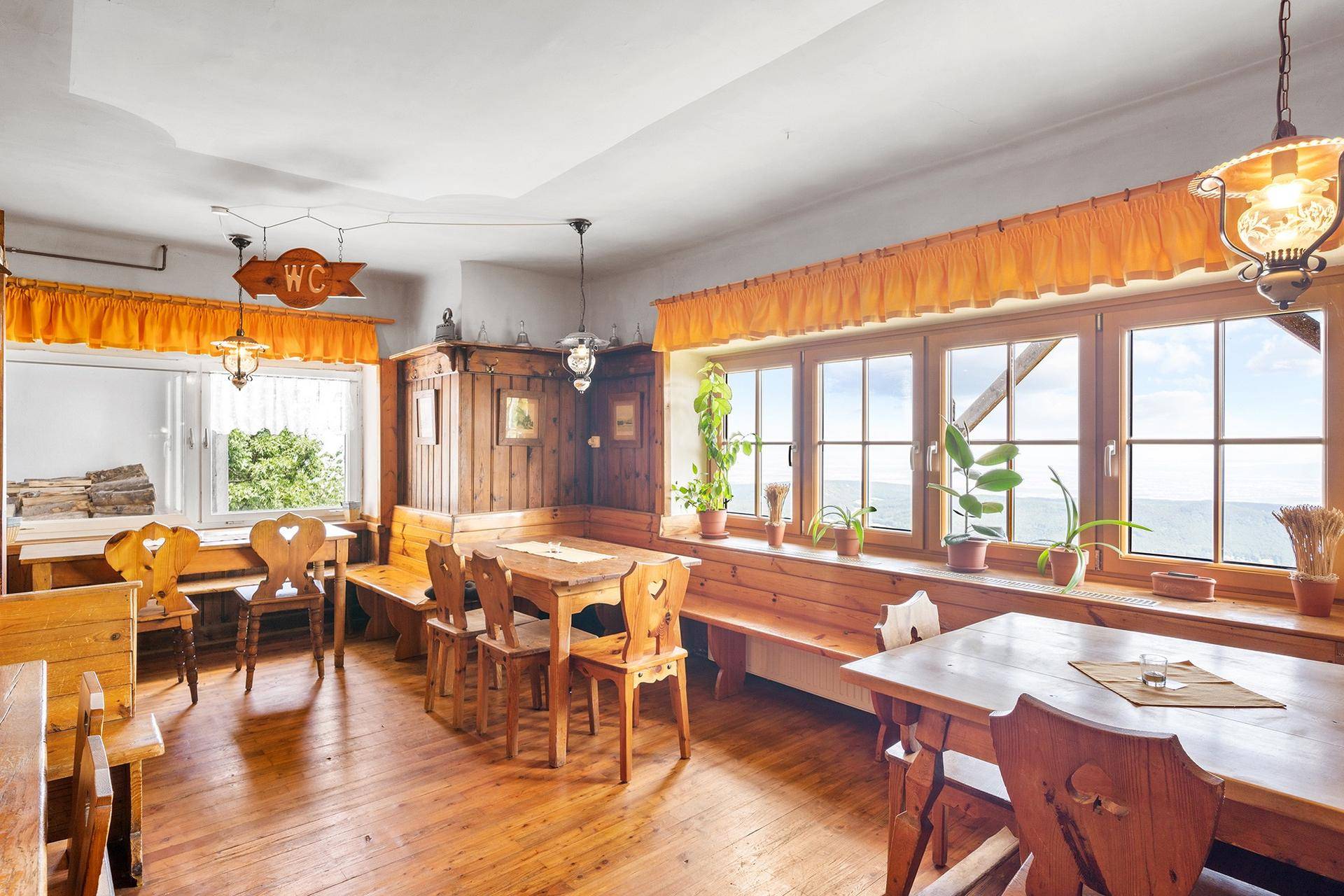 Traditioneller Speisesaal mit Holzböden und -möbeln, großen Fenstern und einem weiten Ausblick.