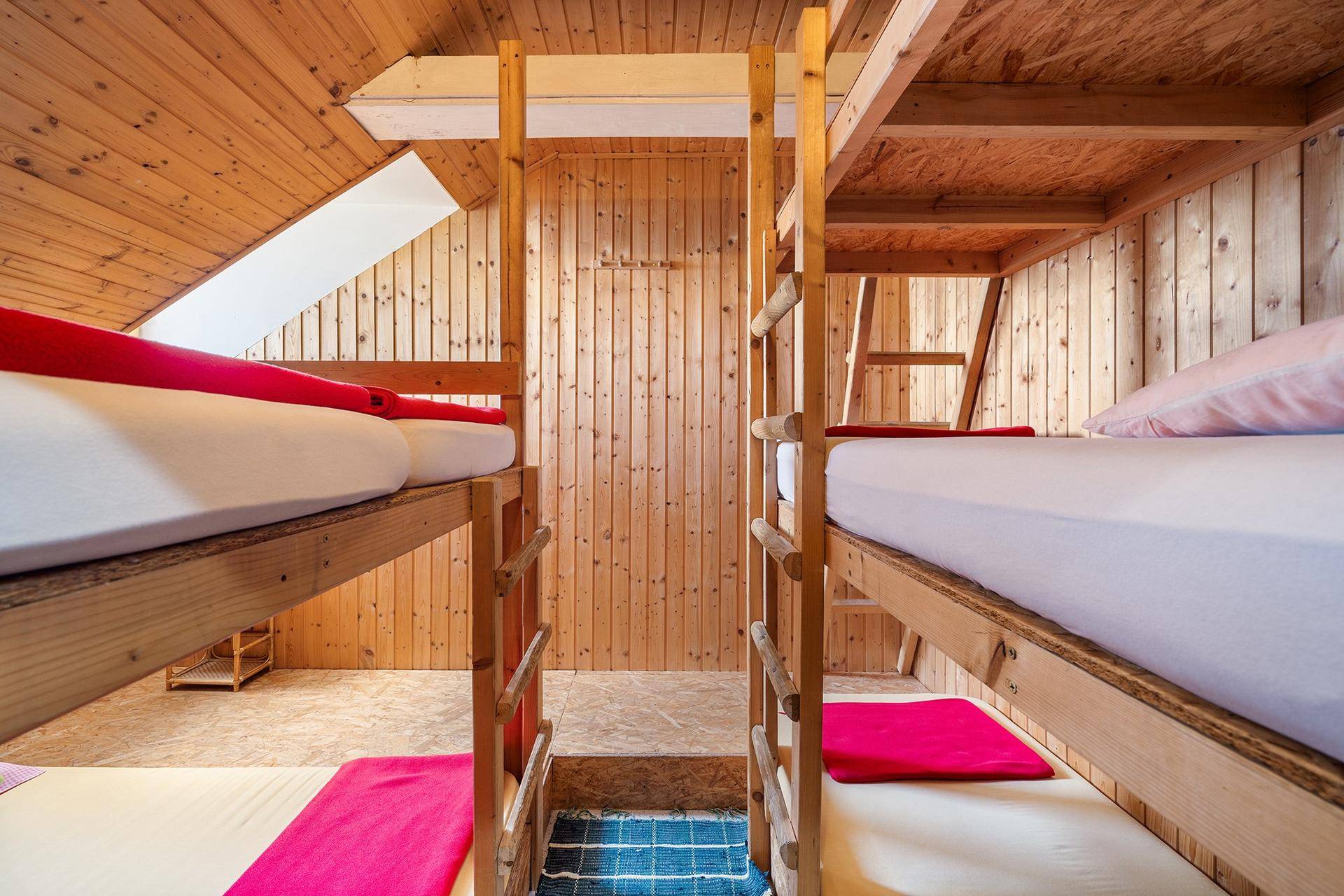 Mehrbettzimmer mit Etagenbetten, Holzverkleidung und schrägen Decken, ideal für Gruppen.