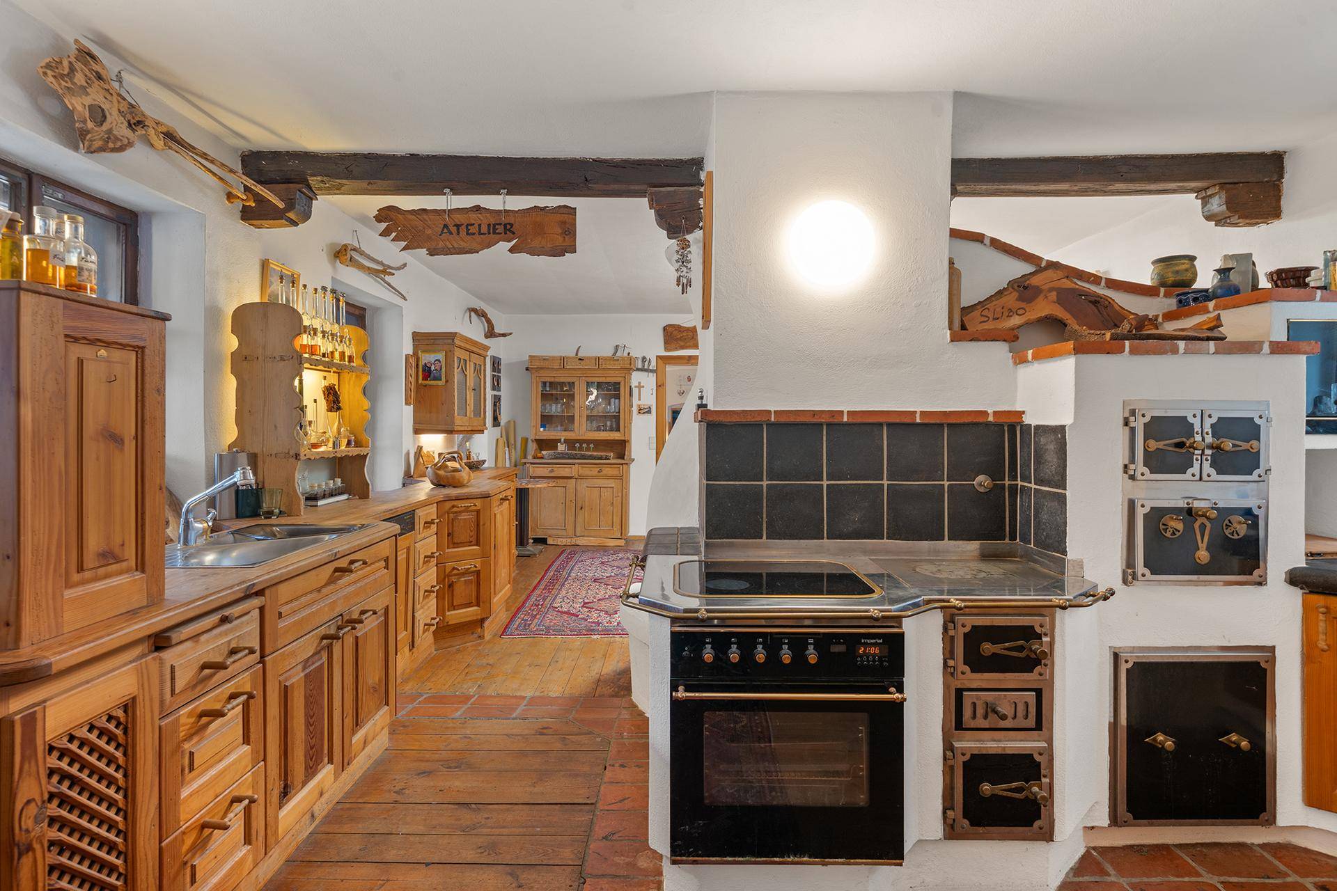 Rustikale Küche mit Holzeinbauten, traditionellem Herd und sichtbaren Holzbalken an der Decke.