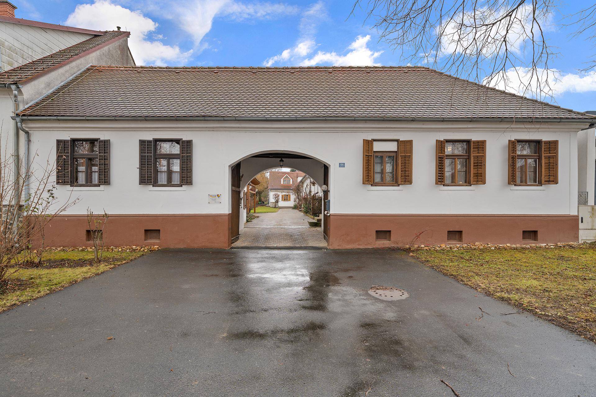 Vorderansicht eines traditionellen Gebäudes mit Torbogen und Holzfensterläden, gut gepflegt.