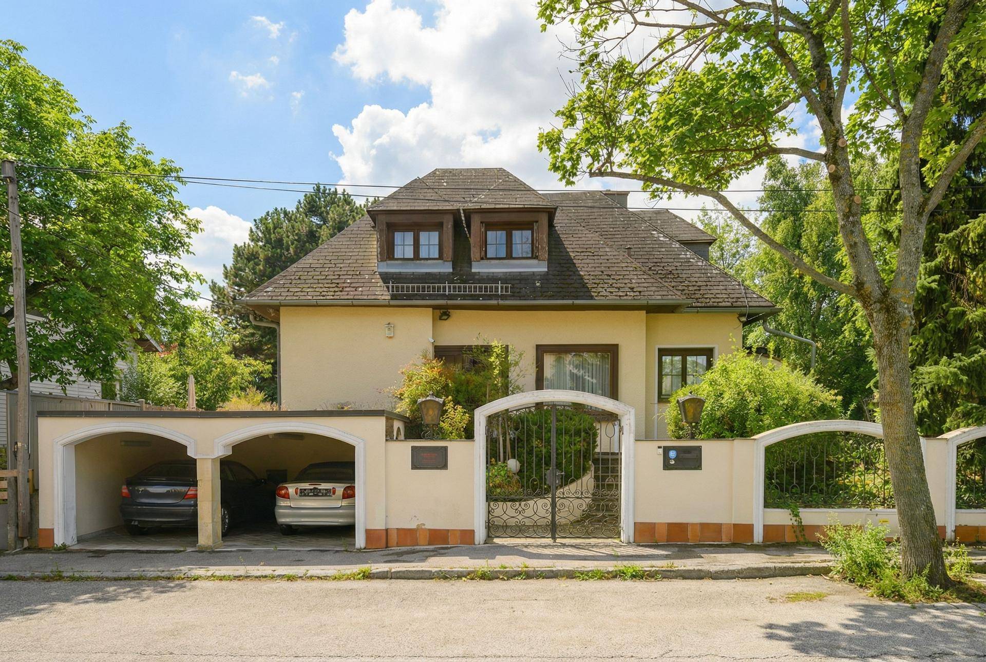 Traditionelles Haus mit Satteldach, Gaubenfenstern und zwei integrierten Carports an der Vorderseite.