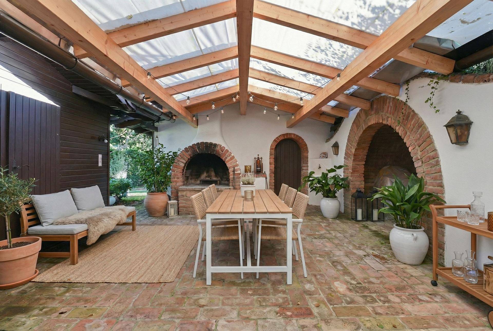 Modernisierter überdachter Essbereich im Freien mit stilvollen Möbeln und Backofen.