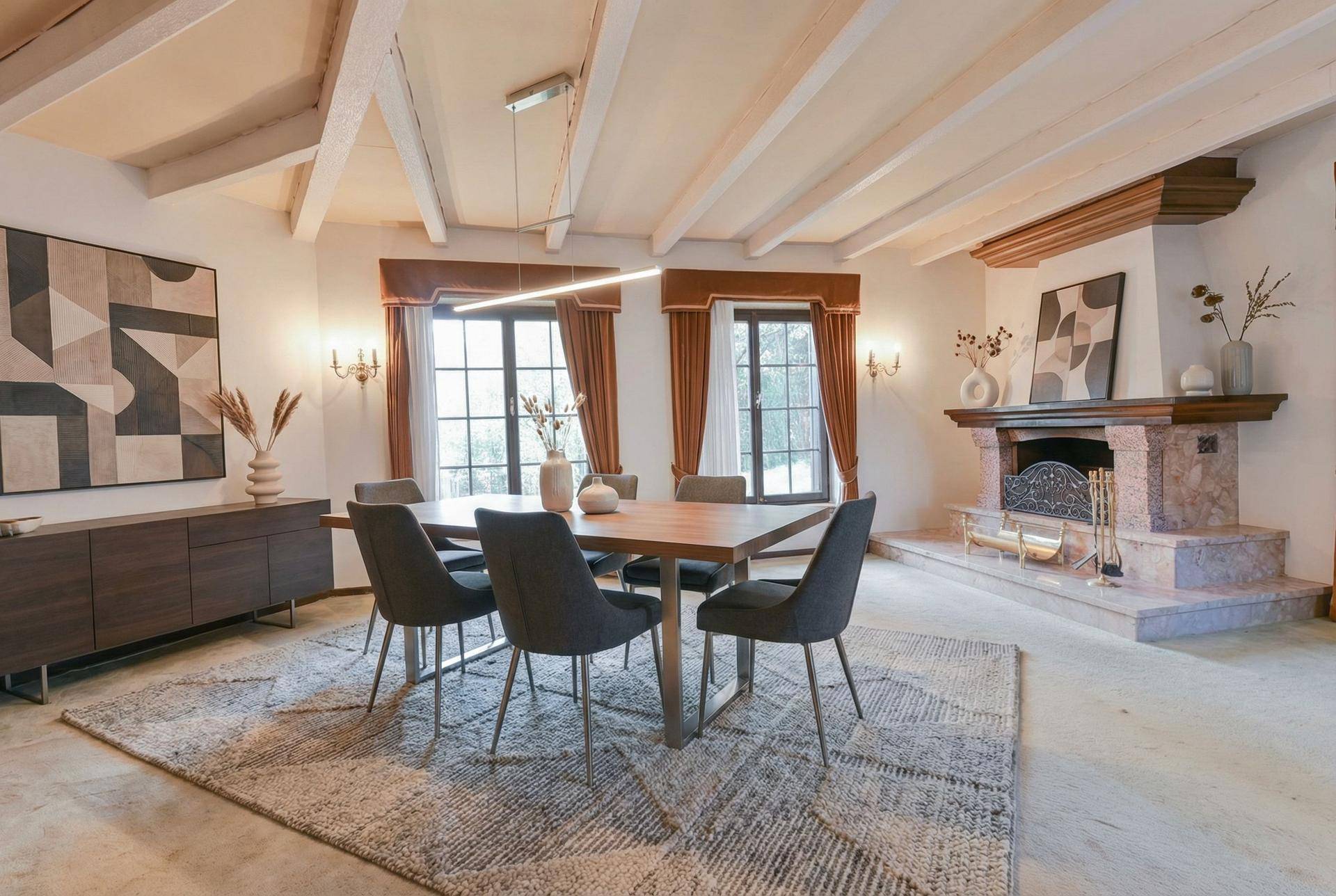 Modernisierter Essbereich mit zeitgenössischem Esstisch, Kamin und sichtbaren Deckenbalken.