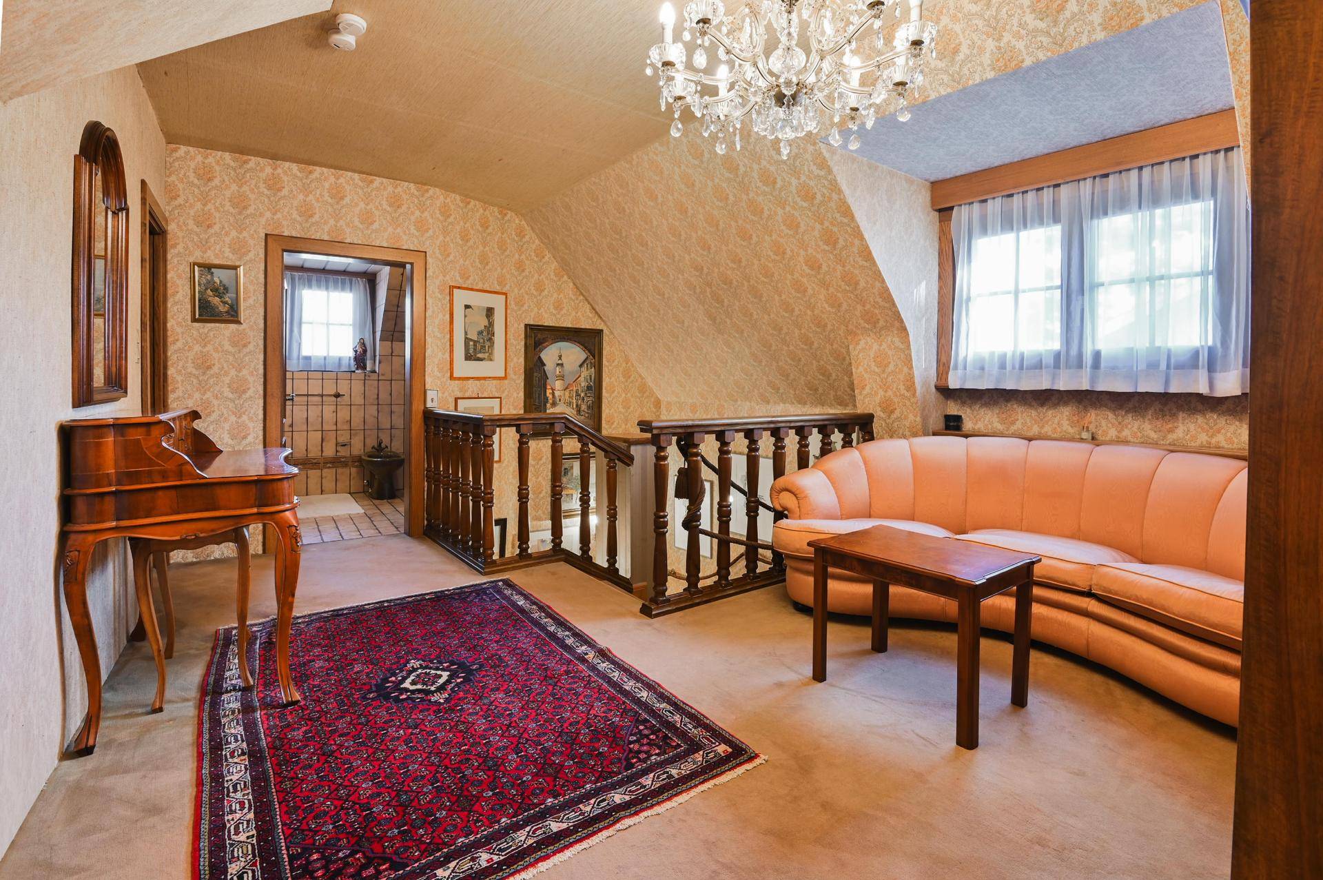 Gemütlicher Flurbereich im Obergeschoss mit Treppe, traditionellen Möbeln und Kronleuchter.