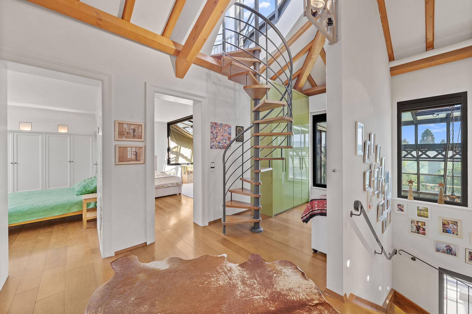 Obere Diele mit eleganter Wendeltreppe, sichtbaren Holzbalken und natürlichem Lichteinfall.