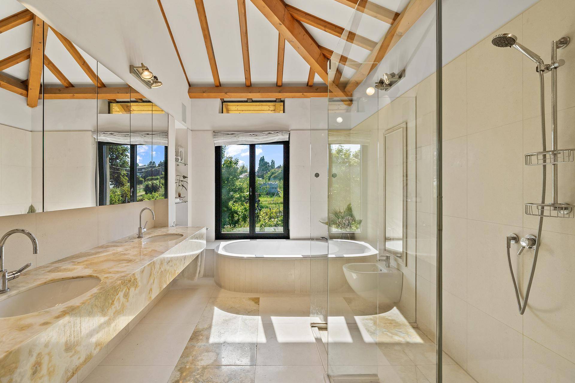 Luxuriöses Badezimmer mit Doppelwaschbecken, Badewanne, begehbarer Dusche und Holzbalken.