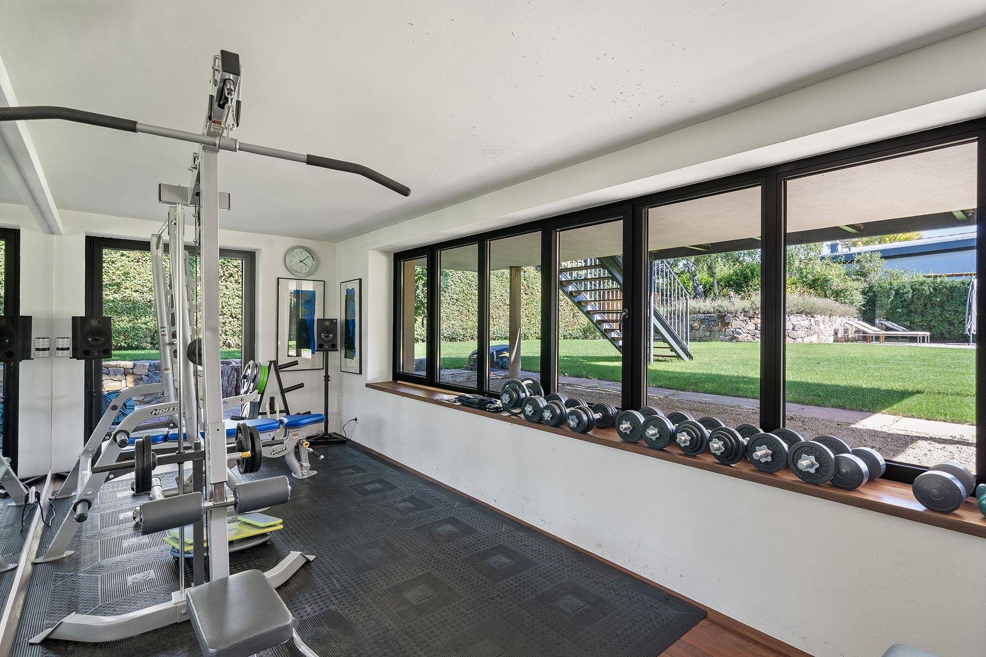Privater Fitnessraum im Untergeschoss mit Trainingsgeräten und Blick in den Garten.
