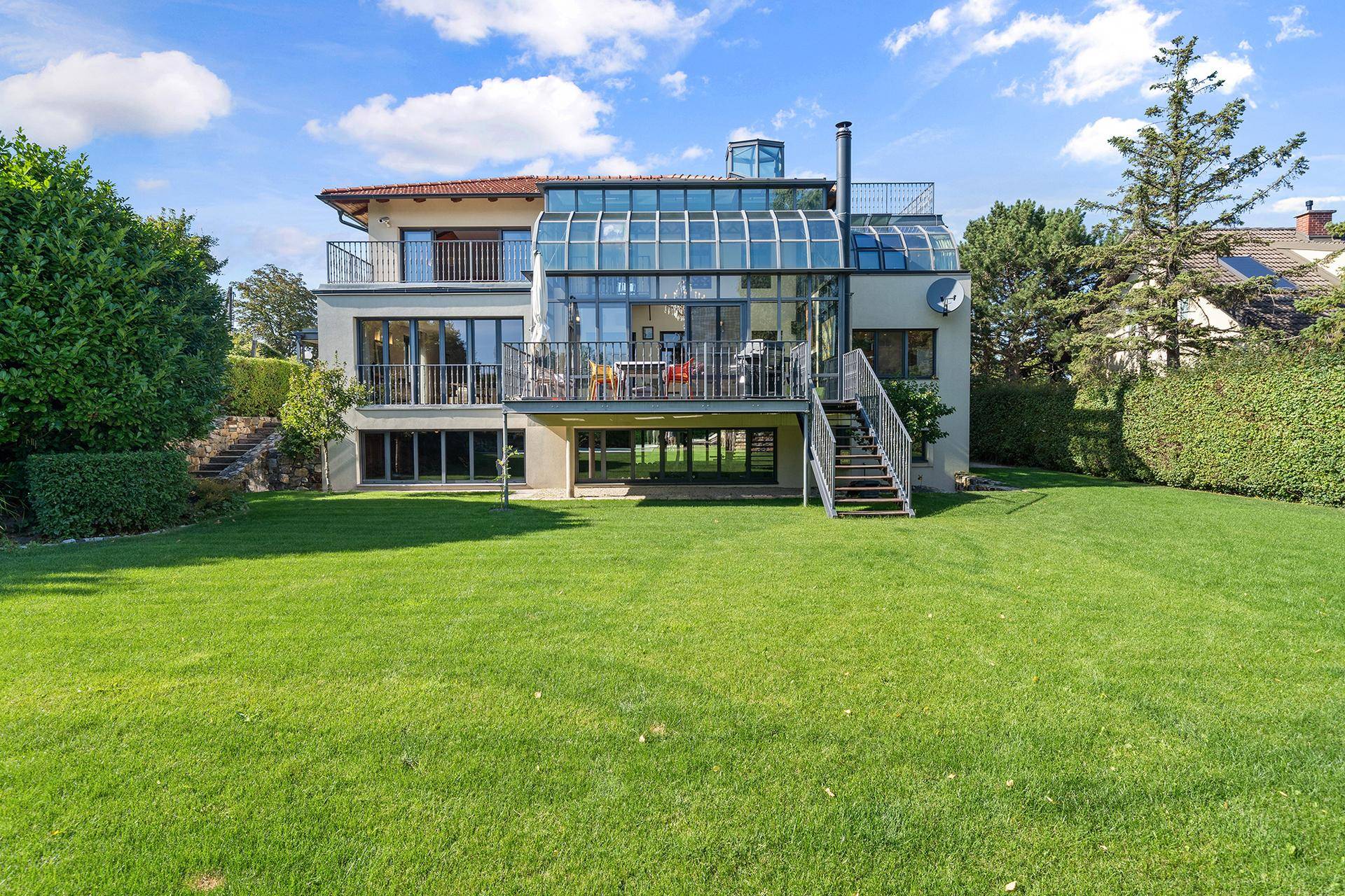Rückansicht der Villa mit großem Garten, Swimmingpool und verglastem Wintergarten.