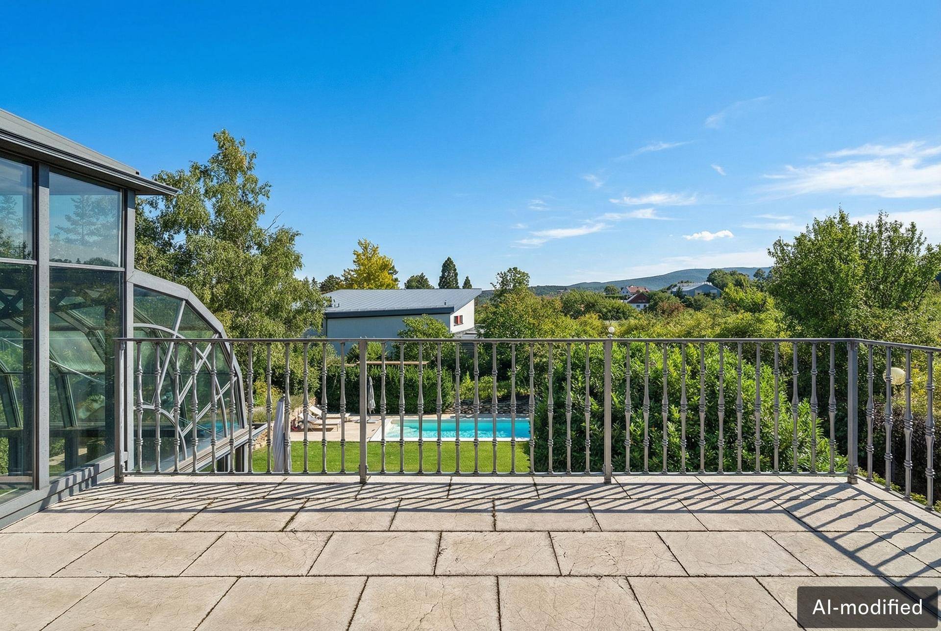 Steingepflasterte Terrasse mit Geländer und weitem Blick über den Garten und die Umgebung.
