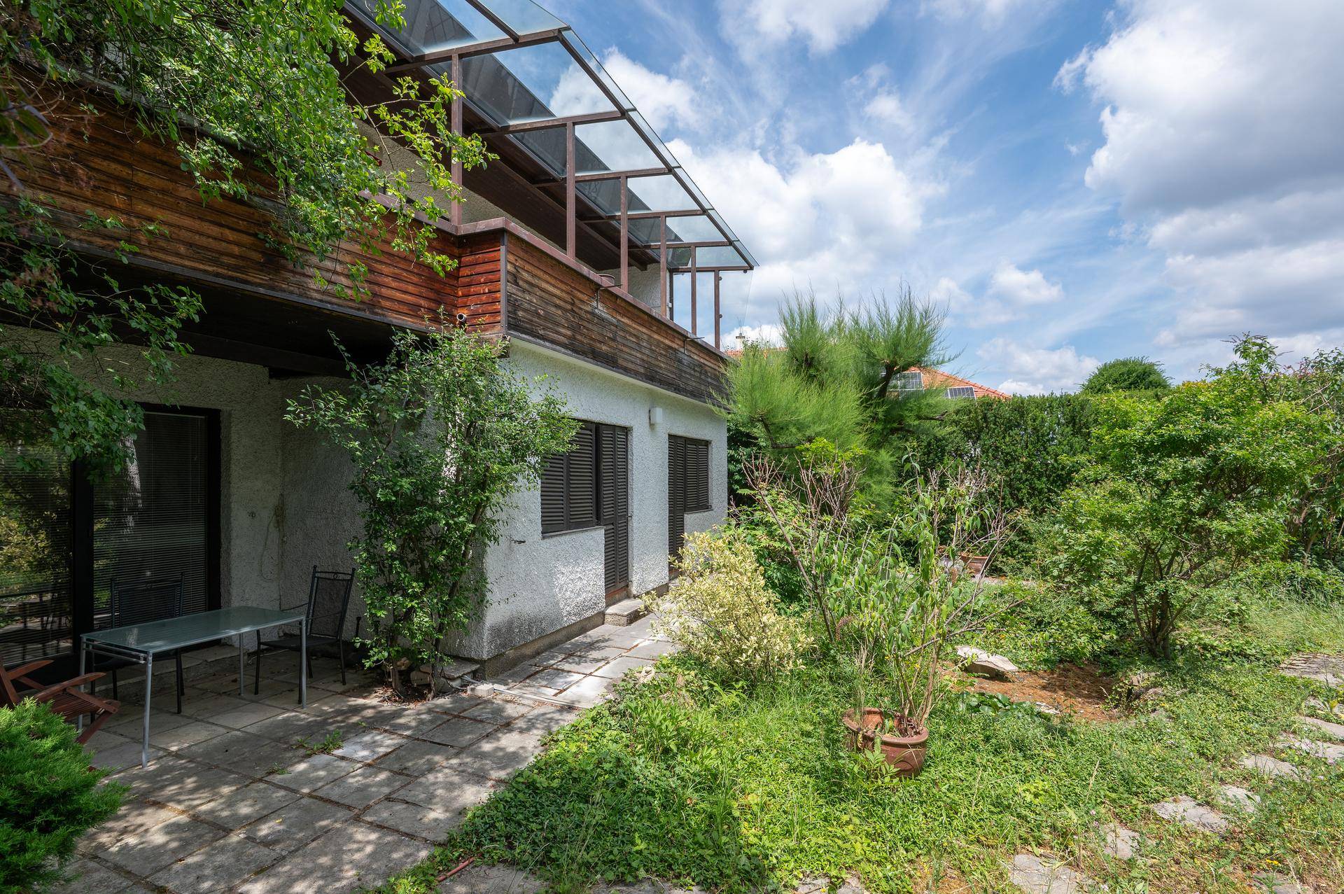 Außenansicht des Hauses mit kleiner Terrasse und naturbelassenem Gartenbereich.