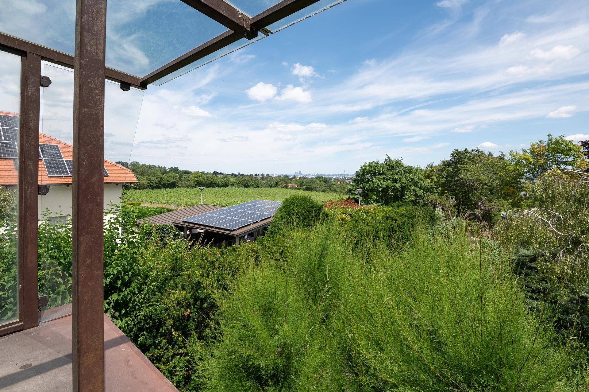 Weitblick von einem Balkon über grüne Landschaft und Dächer mit Solaranlagen.