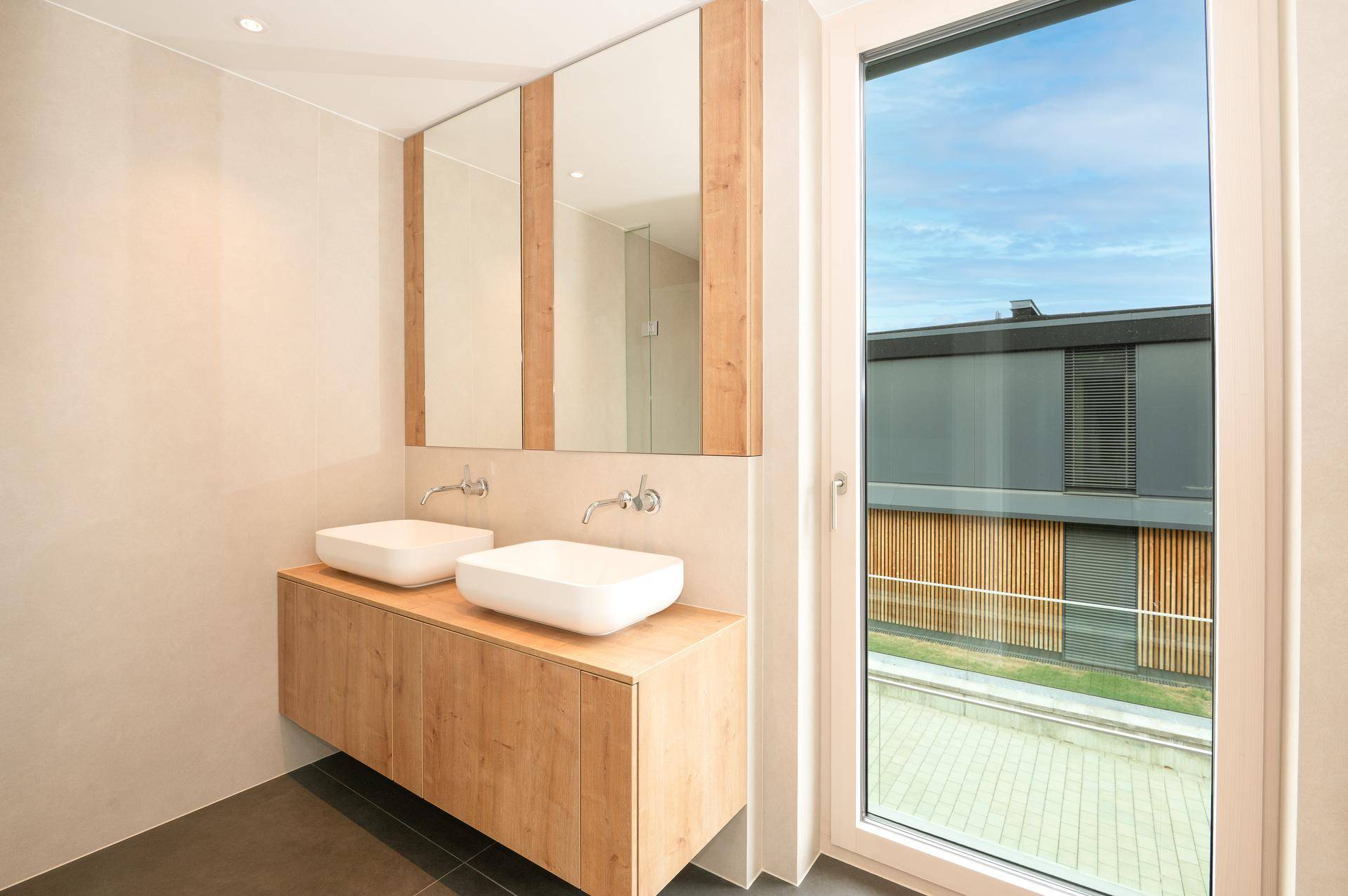 Modernes Badezimmer mit Doppelwaschbecken, großem Spiegel und Fenster mit Ausblick.
