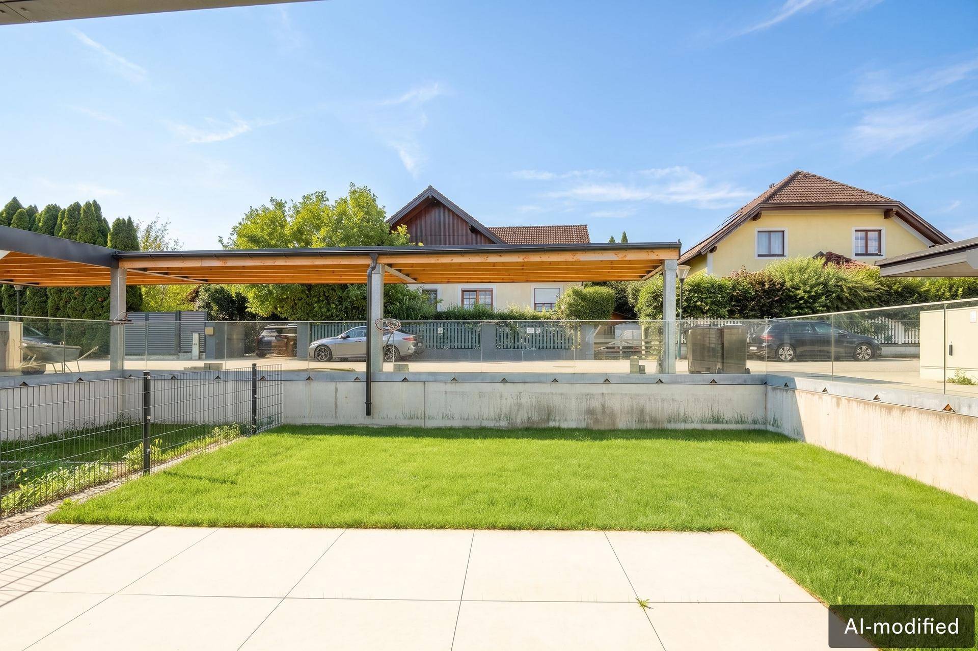 Gepflegter Gartenbereich mit Rasenfläche und überdachtem Carport im Hintergrund.