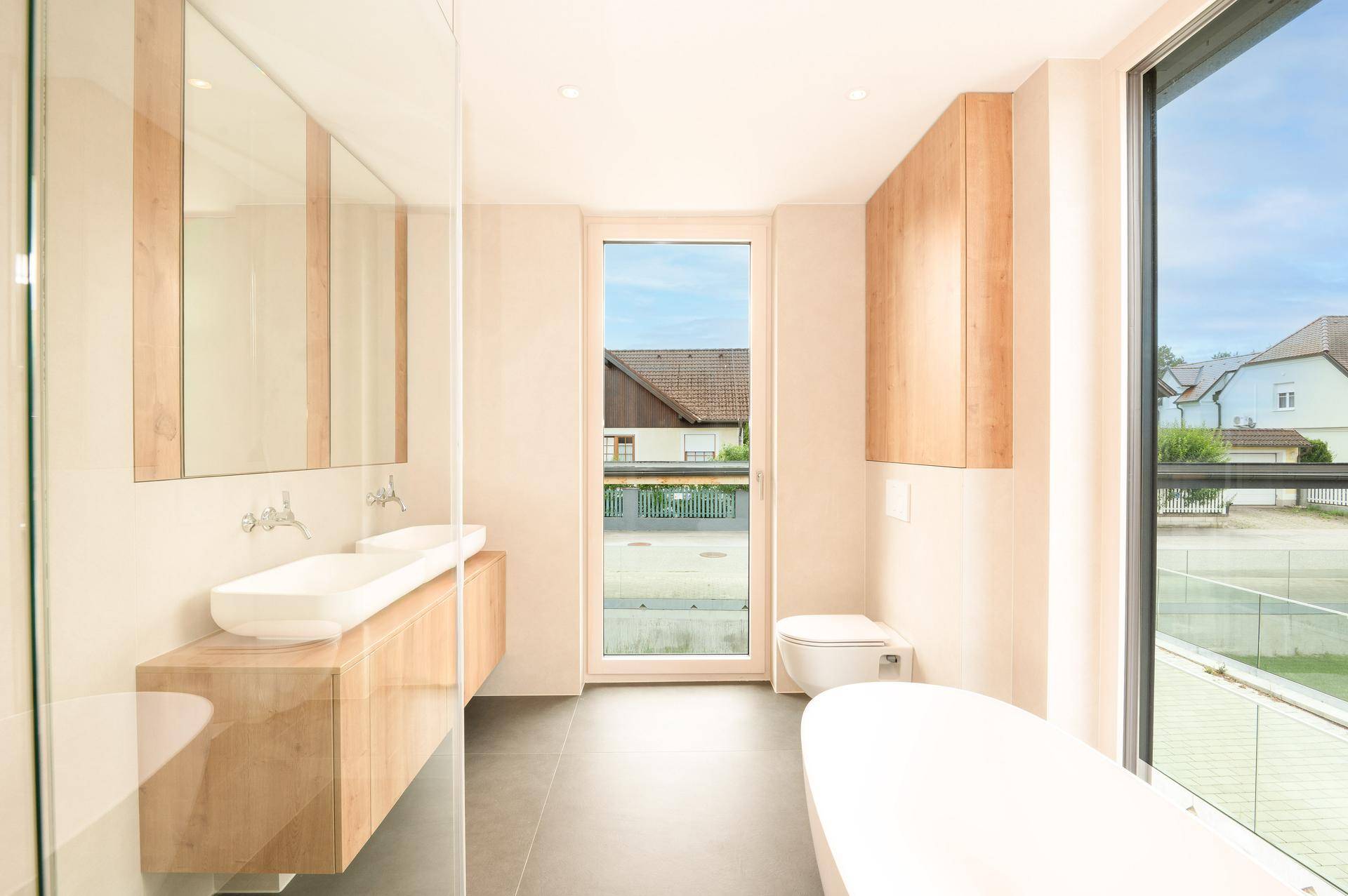 Modernes Badezimmer mit Doppelwaschbecken, freistehender Badewanne und großem Fenster.