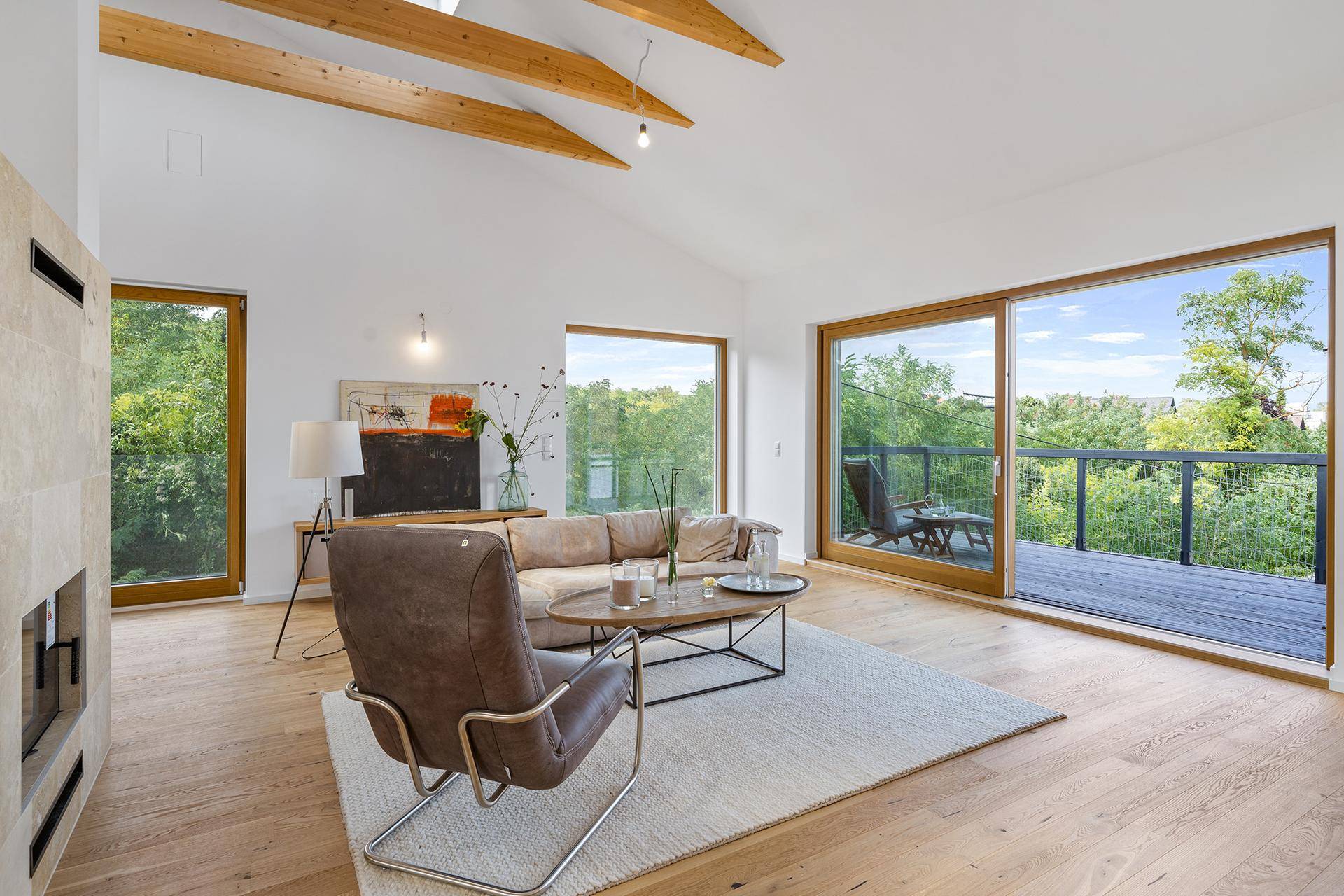 Lichtdurchflutetes Wohnzimmer mit Kamin, Holzbalken und Zugang zum Balkon.