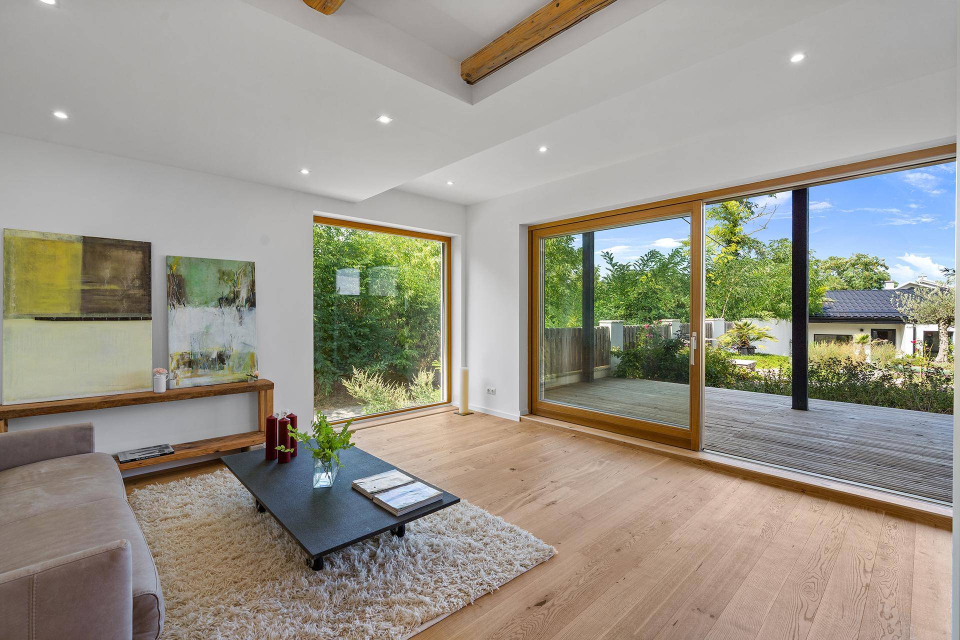 Helles Wohnzimmer mit Holzboden und großen Schiebetüren zur Außenterrasse.