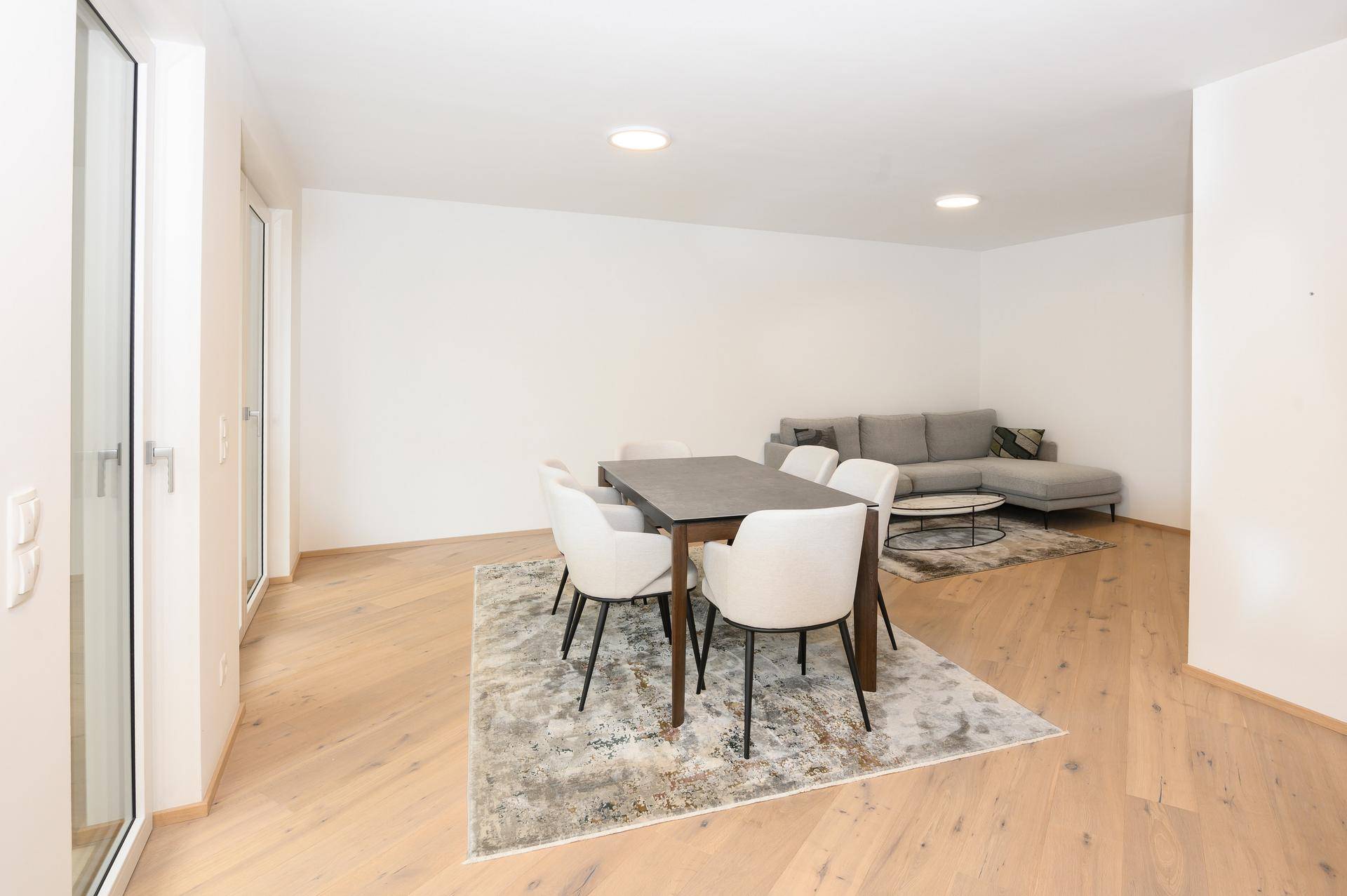 Geräumiger Wohn-Essbereich mit Holzboden, Esstisch und gemütlichem Sofa.