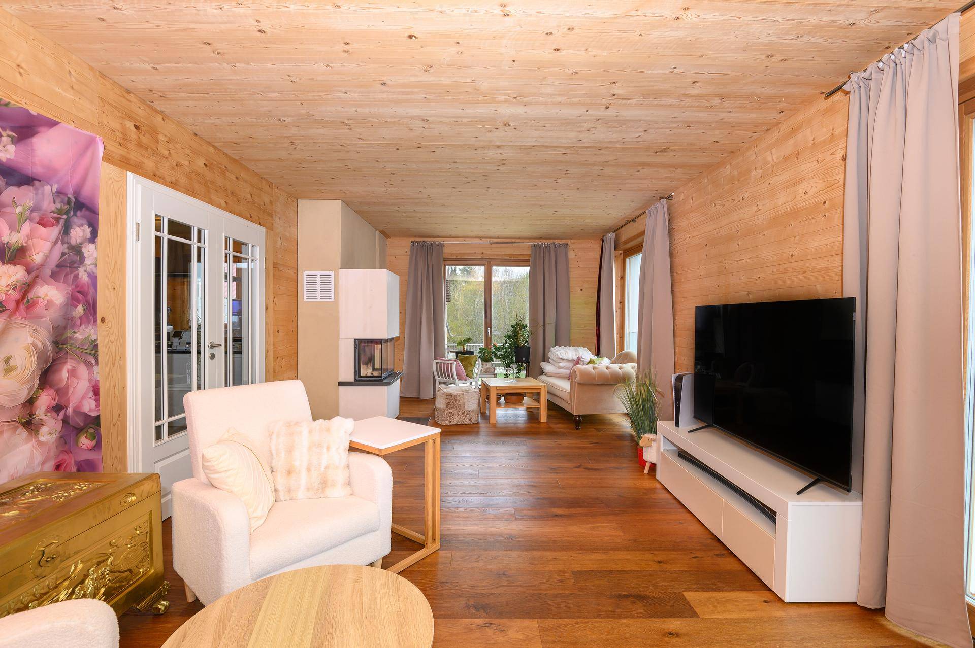 Gemütliches Wohnzimmer mit Holzwänden, Holzboden und modernem Kamin.